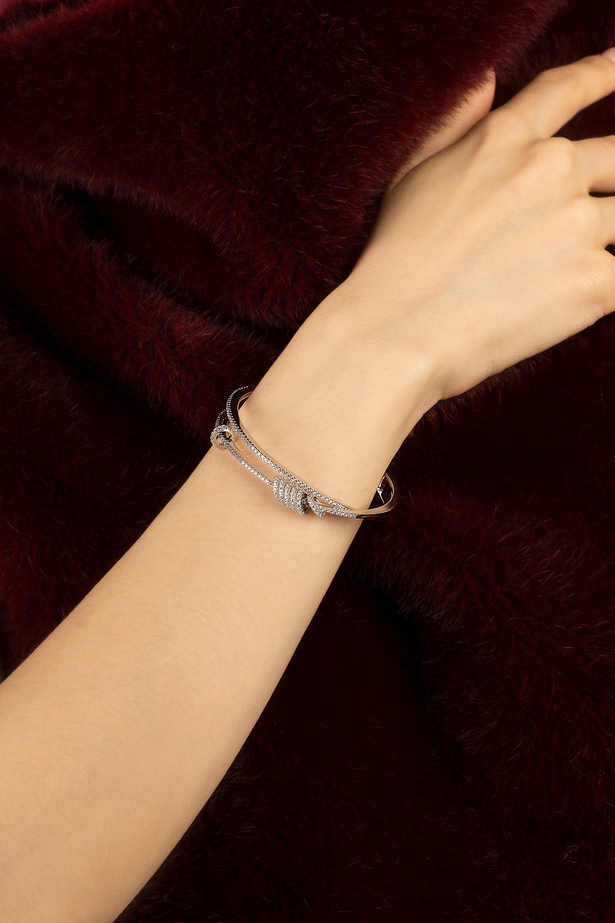 Woman wearing APM bangle, a whisper of rhodium finish against velvet warmth.