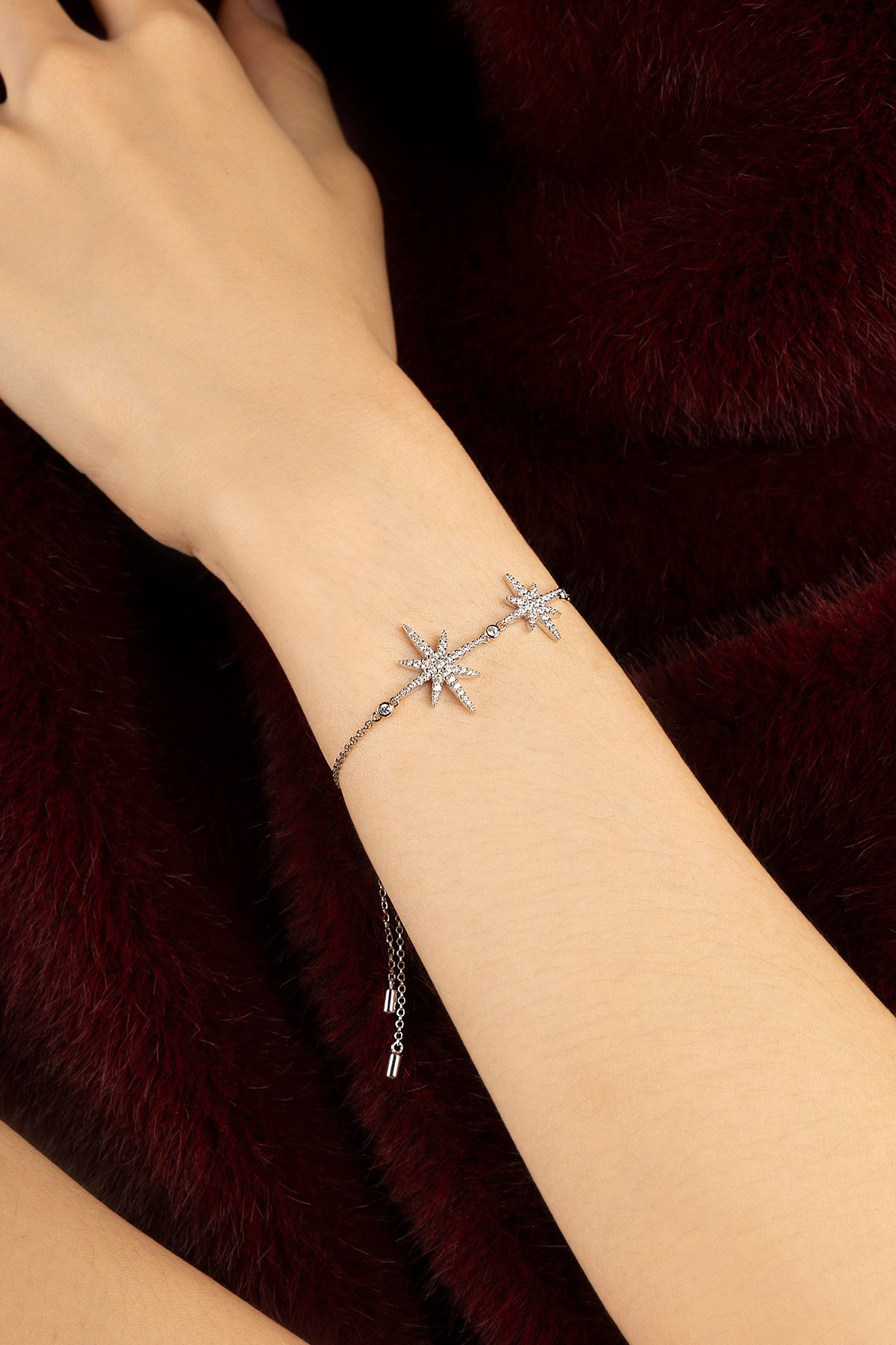 Woman wearing APM Météorites Bracelet, a celestial glow against velvet warmth.