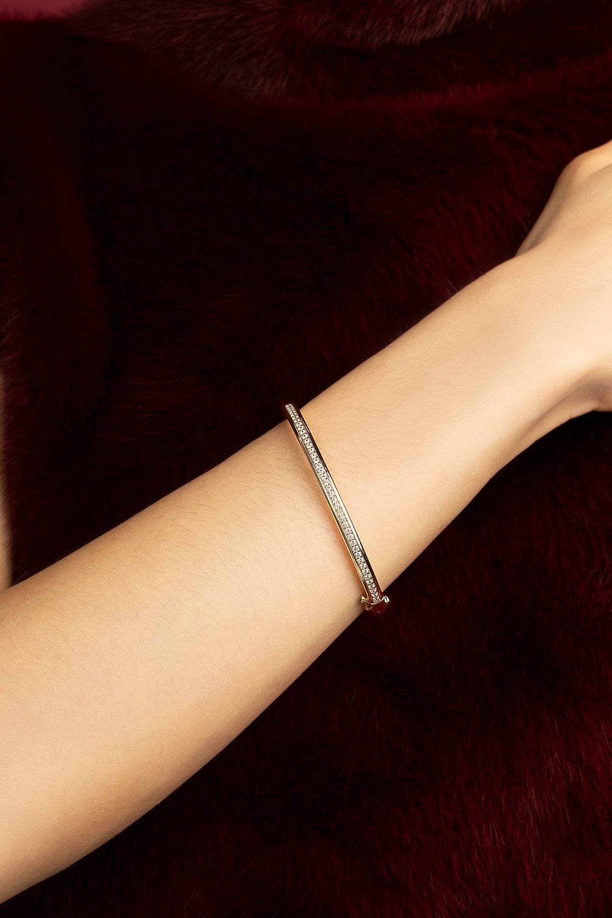 Woman wearing APM Monaco bangle, a whisper of sparkle against velvet warmth.