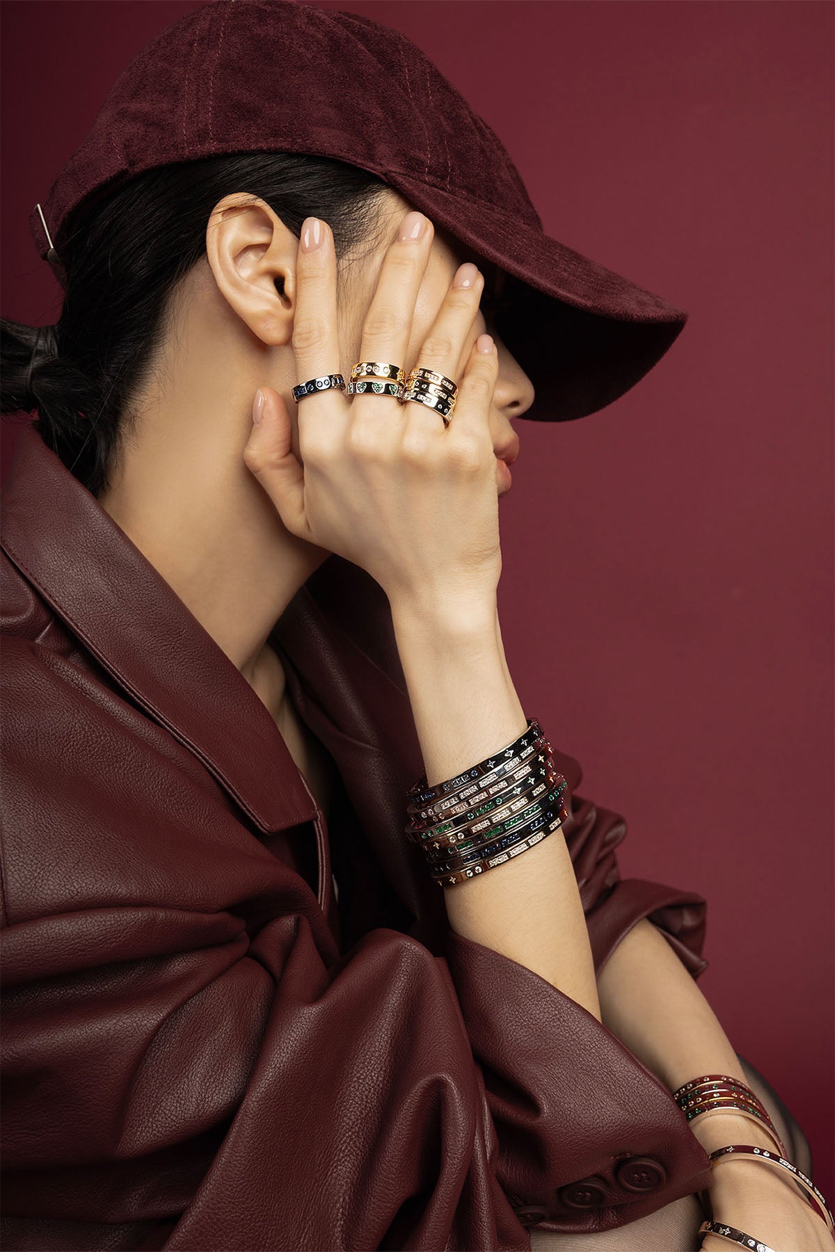 Woman wearing stacked APM Monaco rings and bangles, a bold burgundy statement.