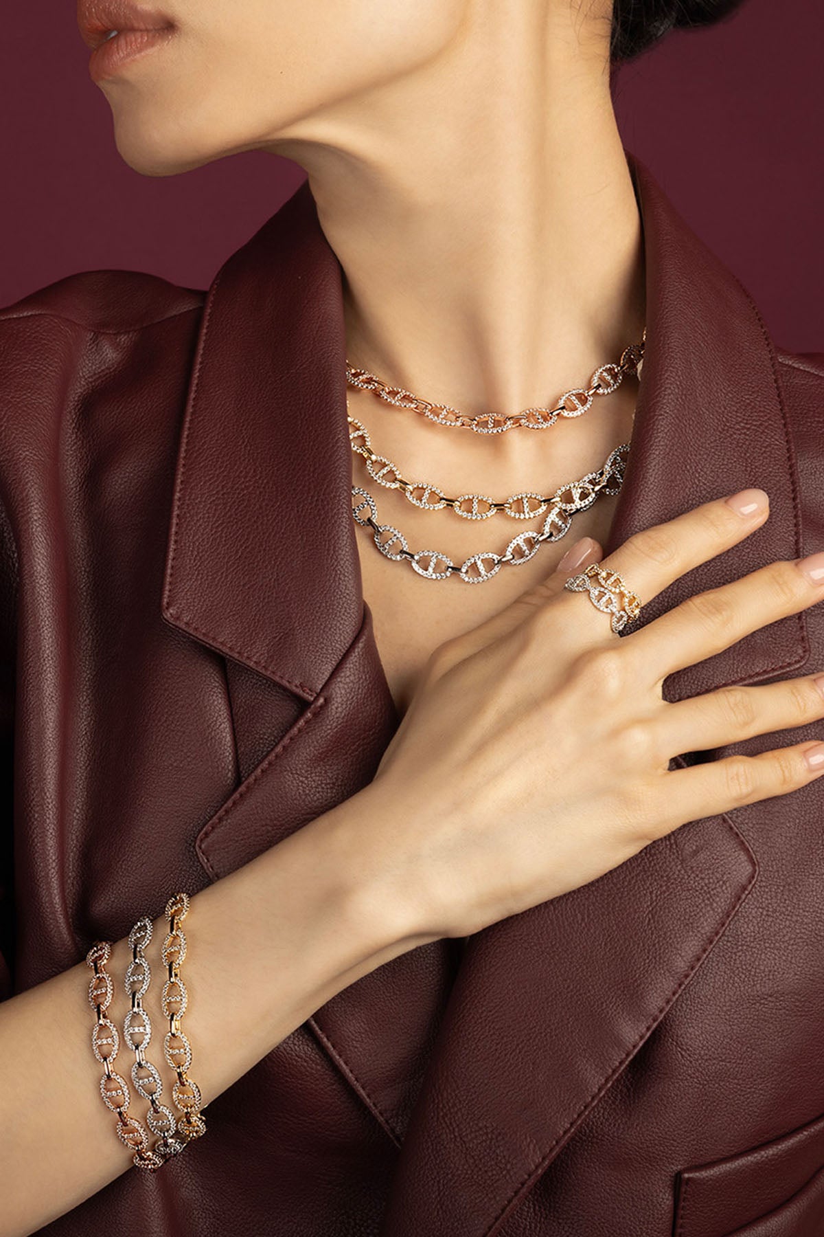 Woman wearing APM Morse chain necklaces, bracelets and ring, layered in bold elegance.