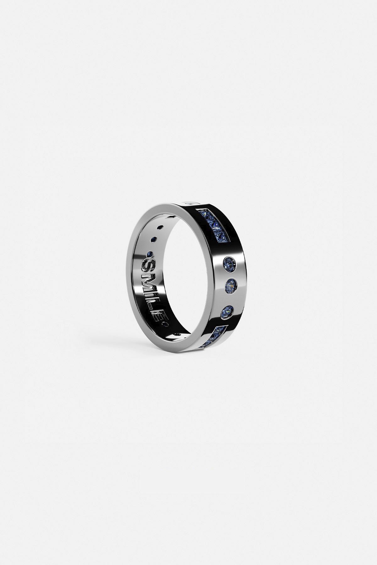 Rings APM Monaco. Silver ring with a row of blue gemstones on the top and 'SMILE' engraved inside.