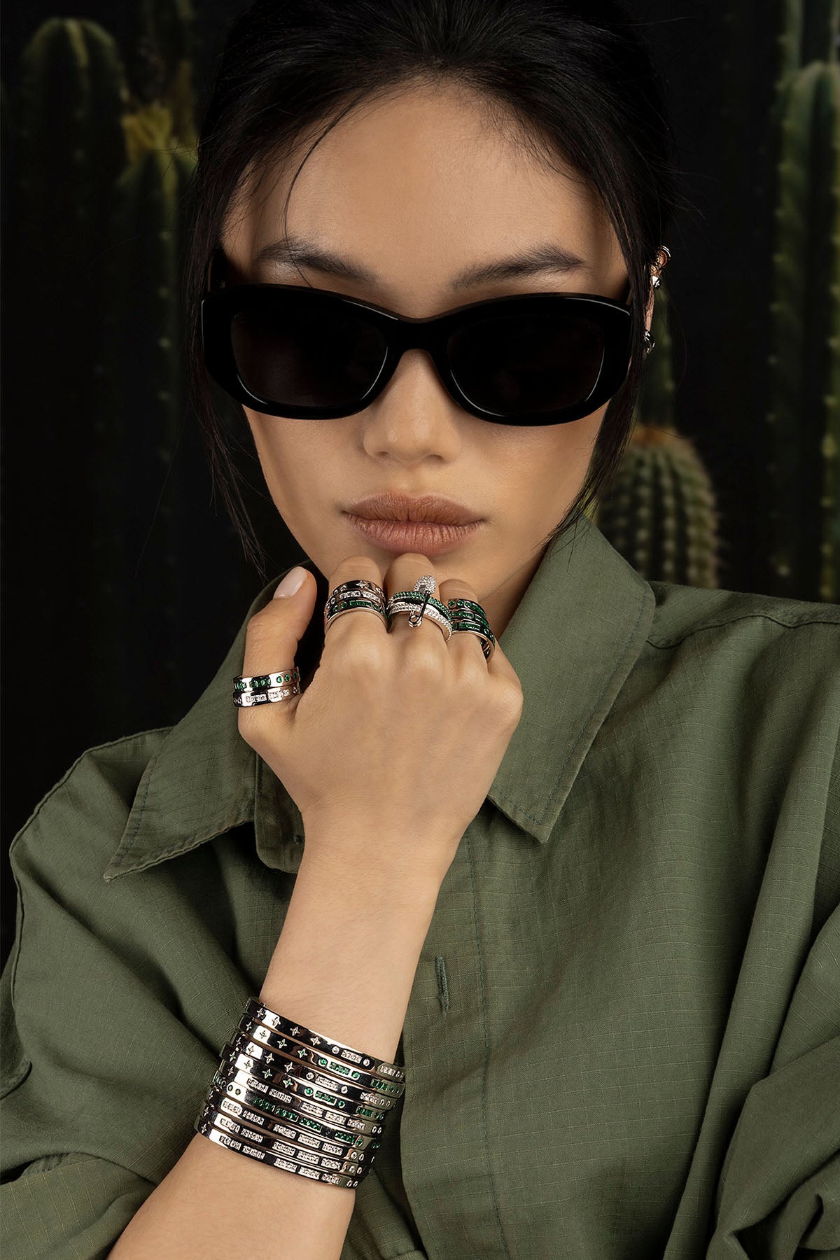 Model wearing sunglasses and multiple rings with a cactus background
