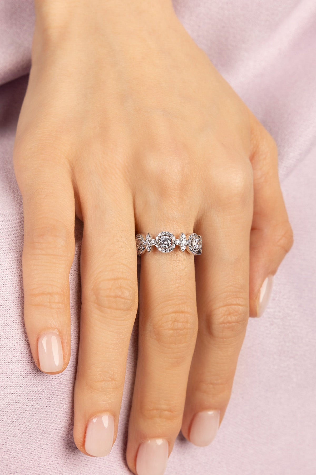Hand wearing a zirconia ring on a pink background
