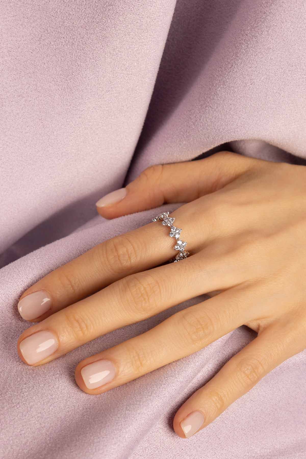 Hand wearing a zirconia ring on a soft pink fabric background