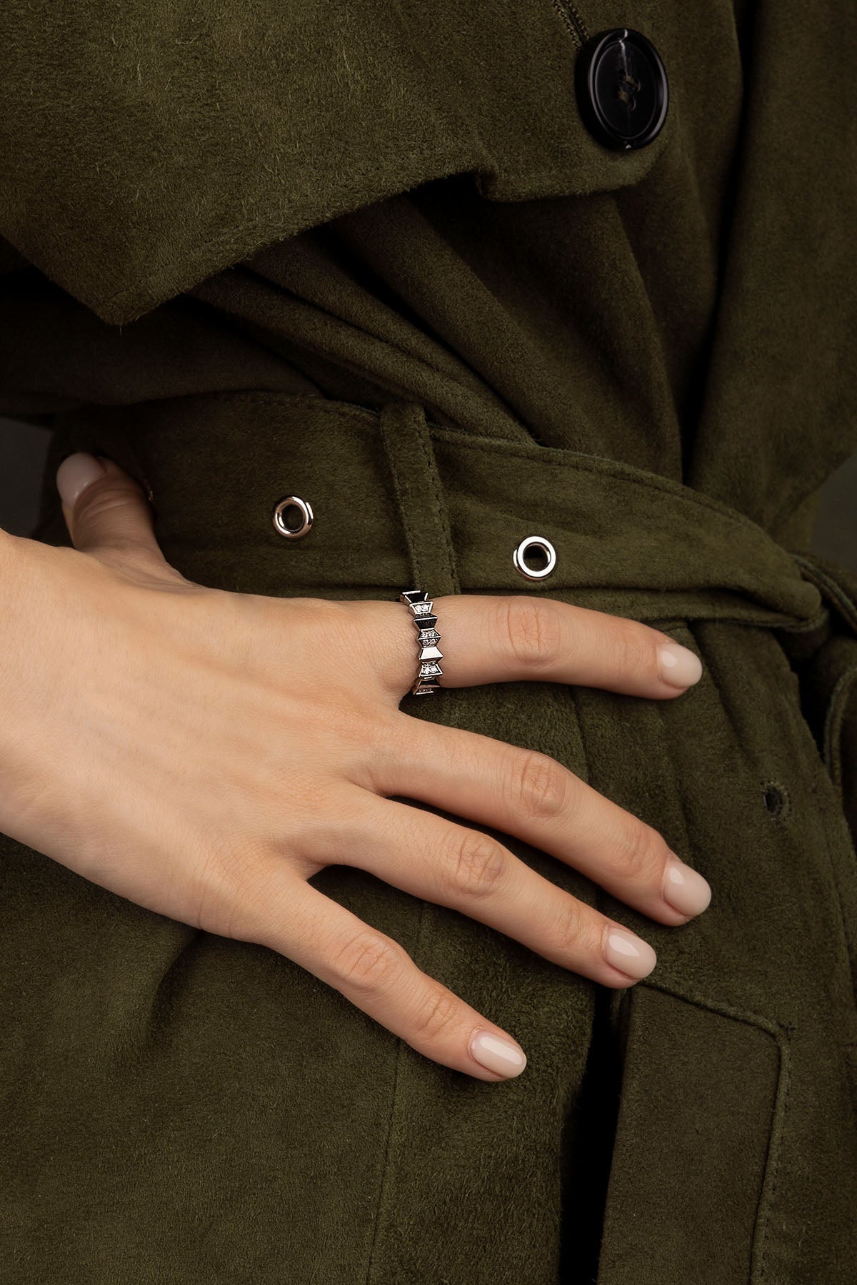 Close-up of a hand wearing a ring on a green coat background
