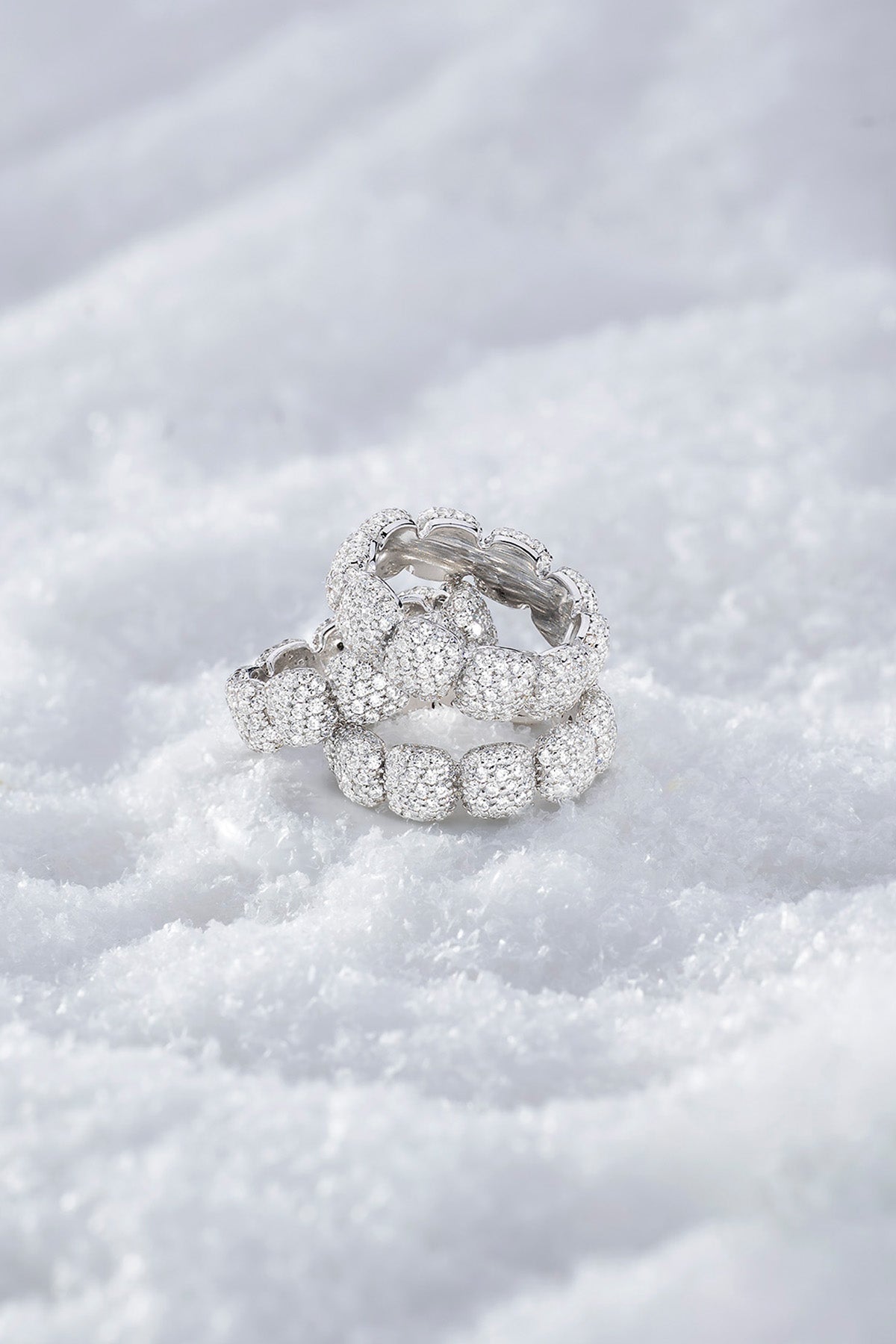 Stack of APM MONACO silver pave rings on a snowy surface
