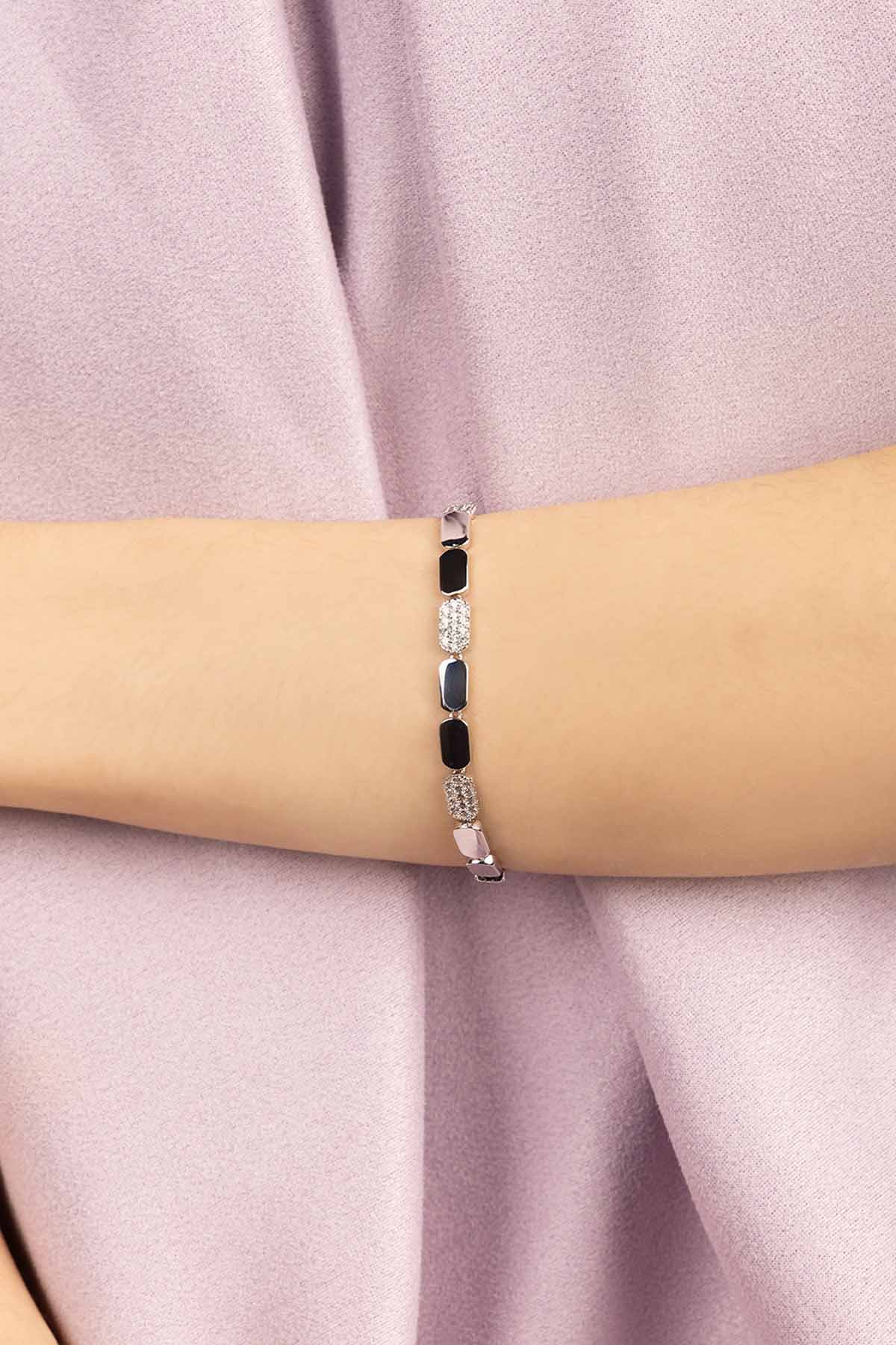 Bracelet with white sones and silver on a wrist against a pink fabric background