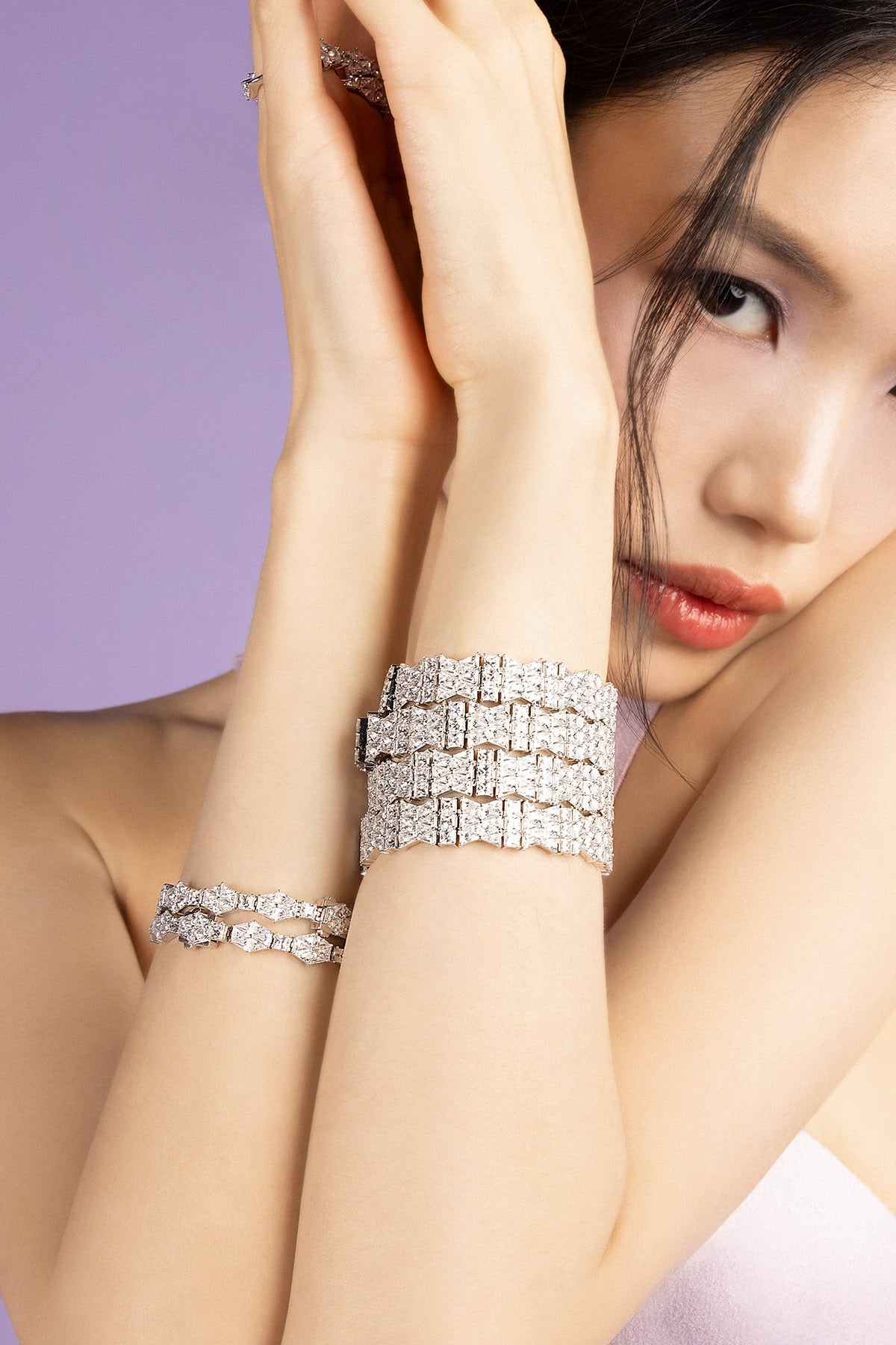 Silver bracelet on a person's wrist with a soft pink fabric background