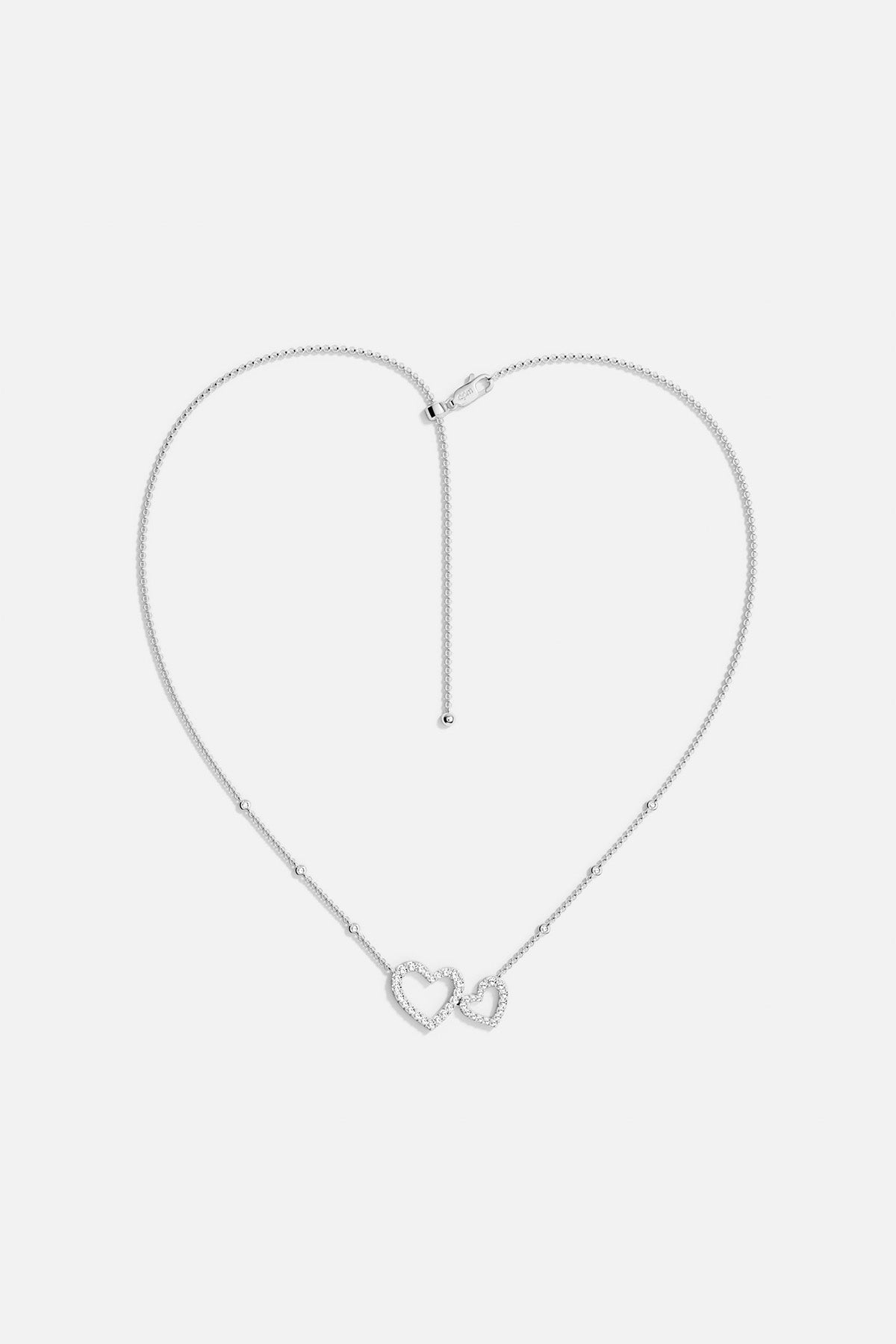 APM MONACO necklace in silver with heart-shaped pendants on a light gray background