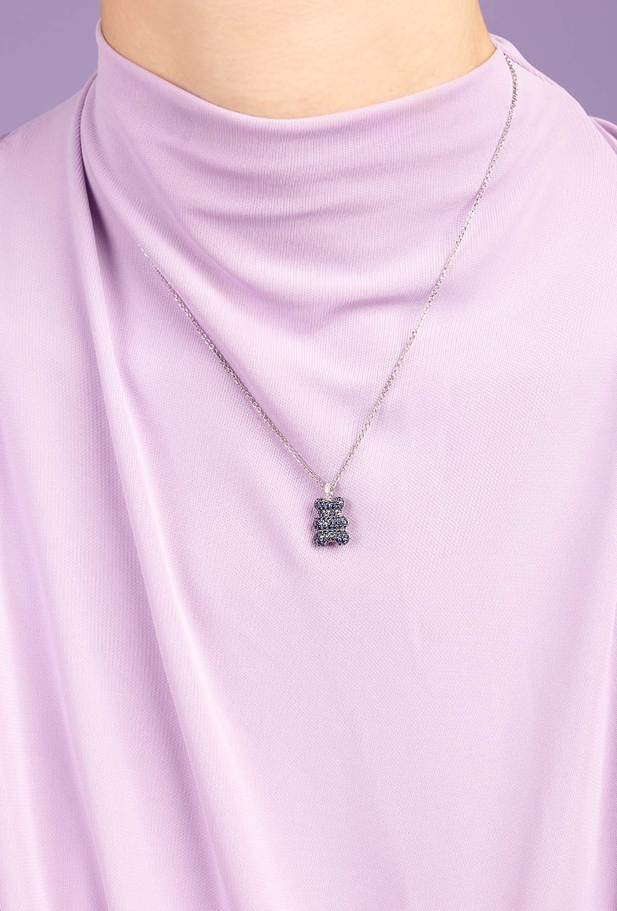 Necklace with a pendant on a person wearing a light purple top against a matching background