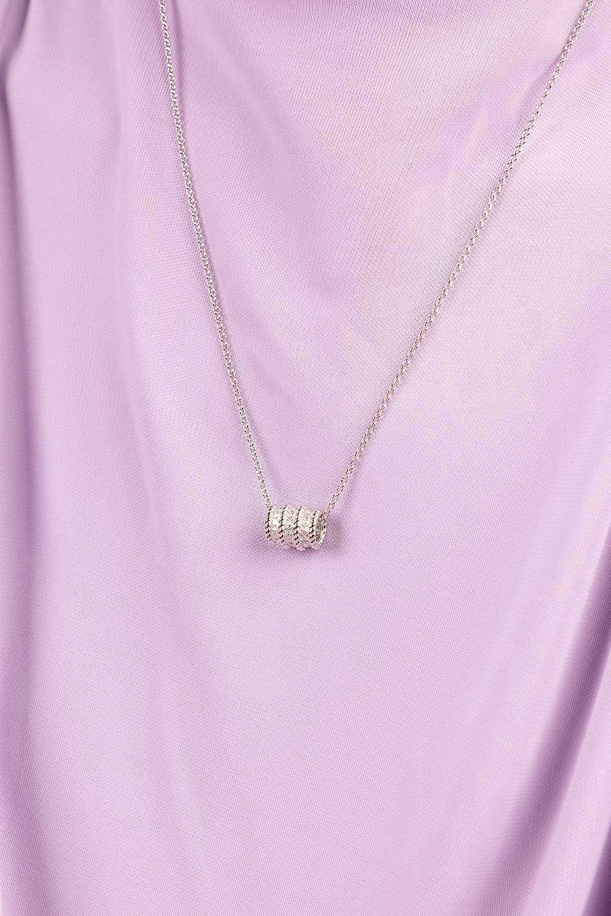 Silver necklace with a torsade pendant on a light purple fabric background