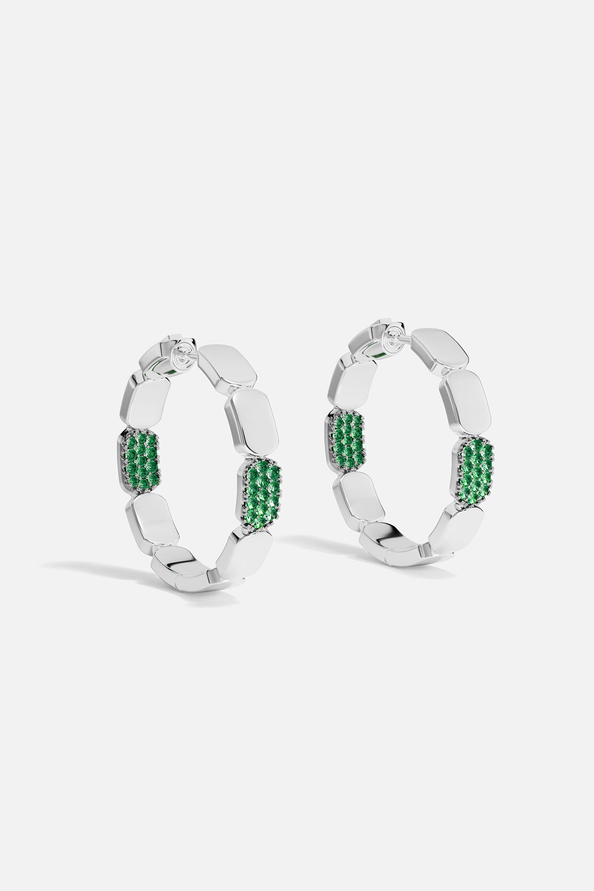 Silver hoop earrings with green stones on a white background