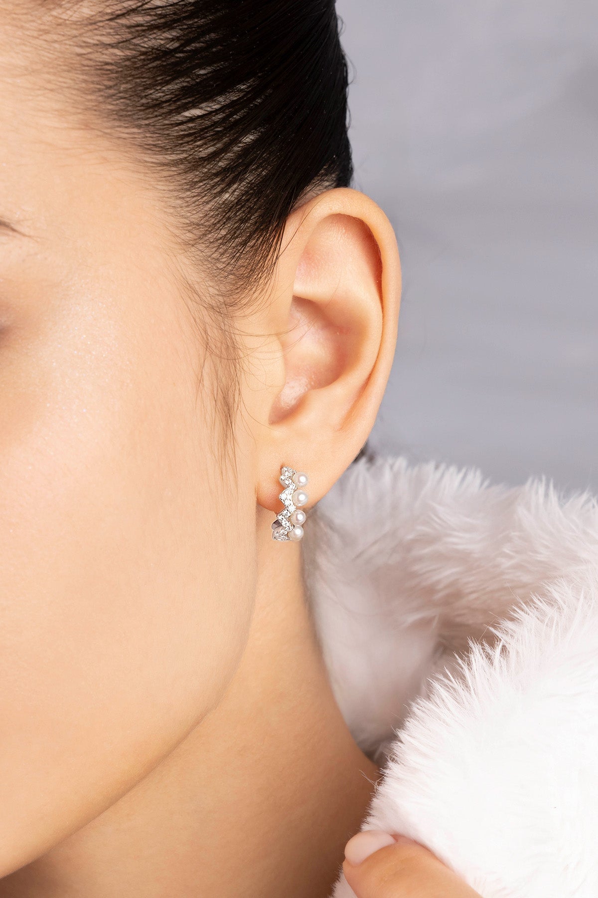 Close-up of an ear wearing a stones and pearls earring with a blurred background