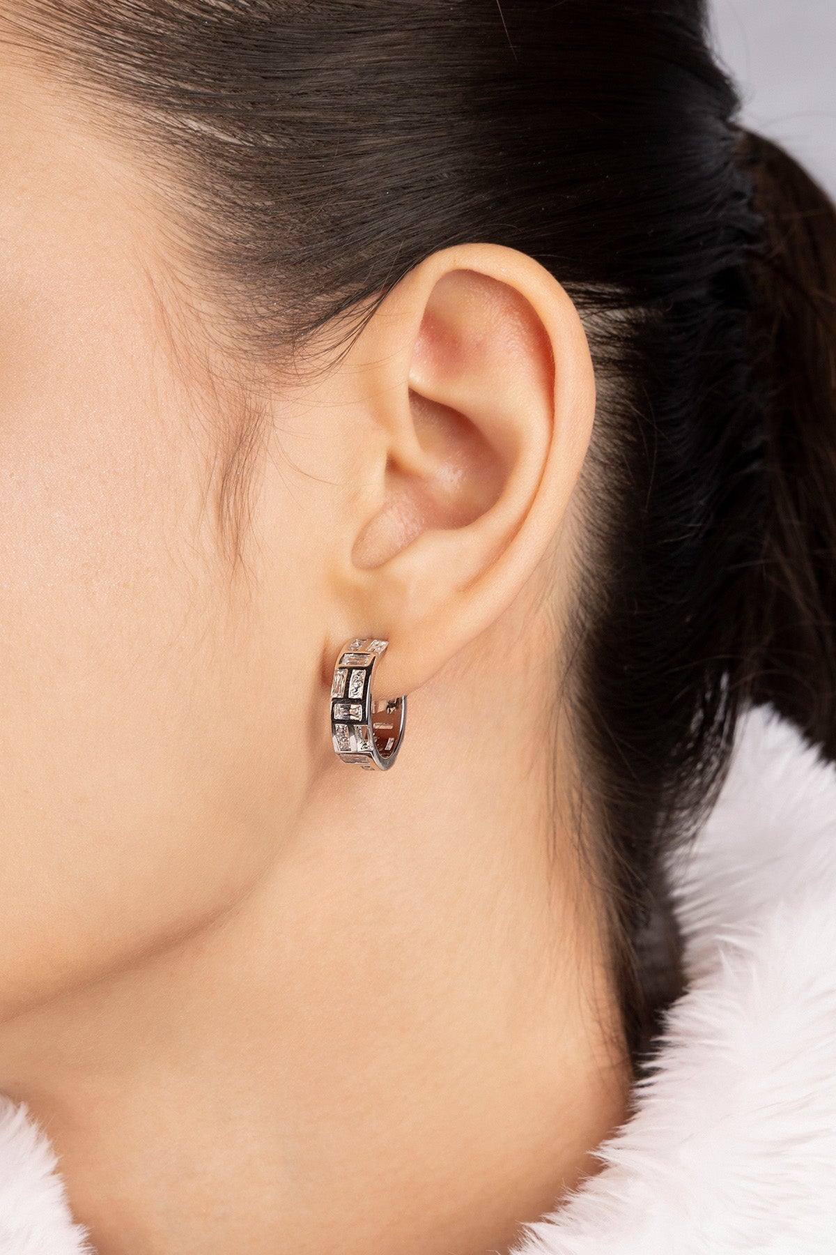 Close-up of APM MONACO labyrinth hoop earring worn by a model with a neutral background