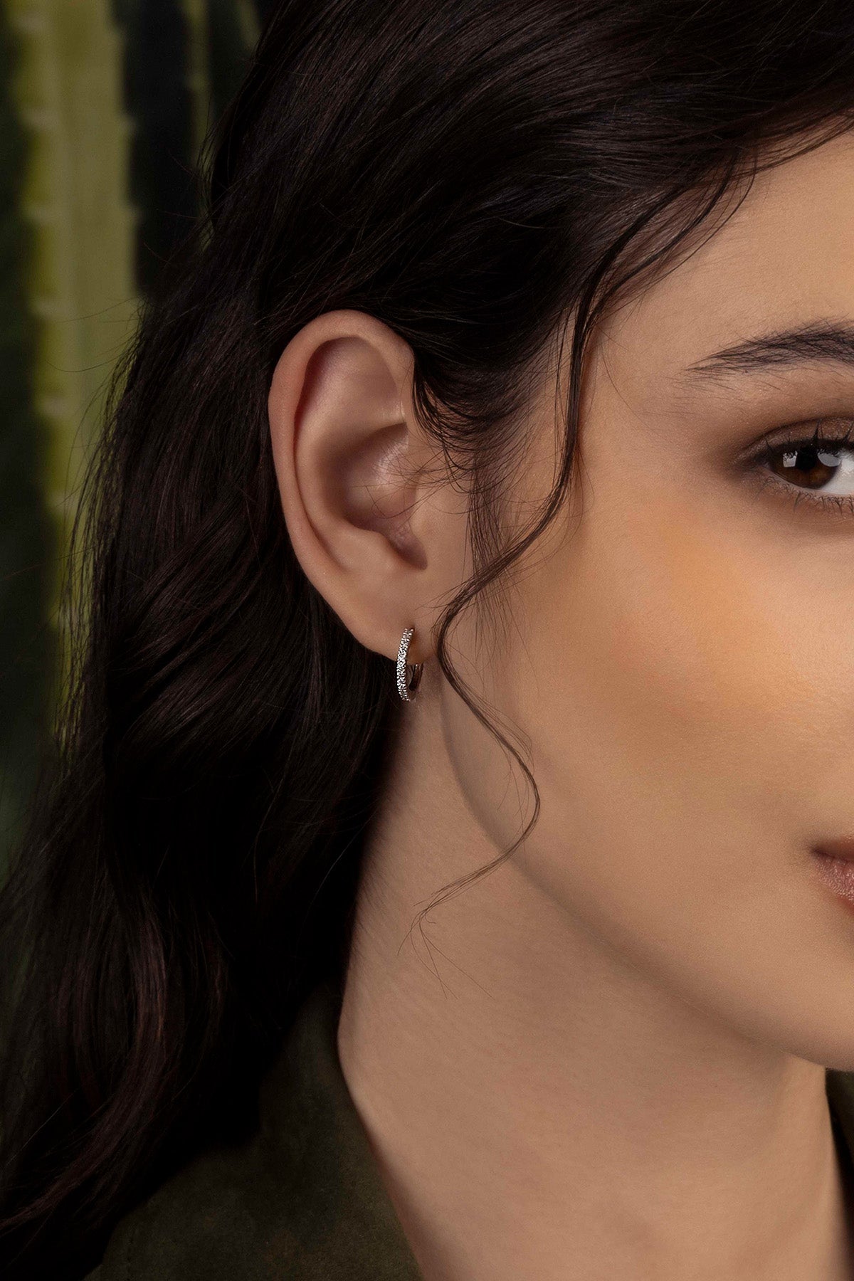 Close-up of a woman wearing a silver earring with a blurred background