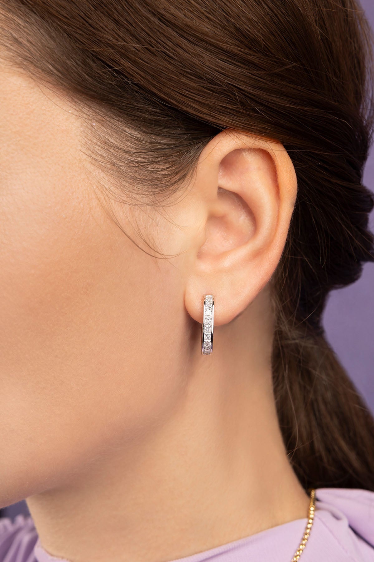 Close-up of a person wearing a silver hoop earring with a blurred background