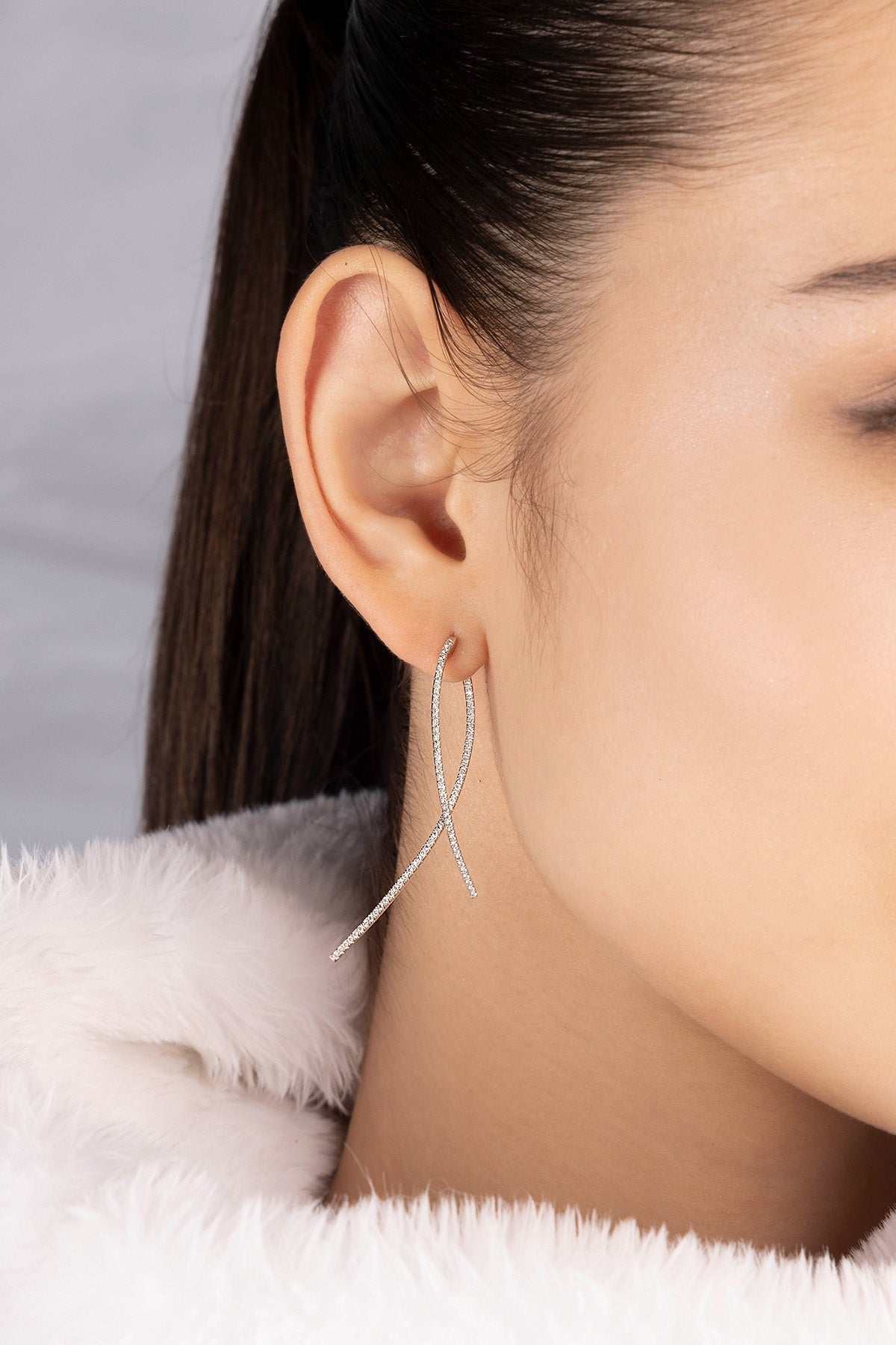Close-up of a model wearing a silver APM MONACO earring with dropping design