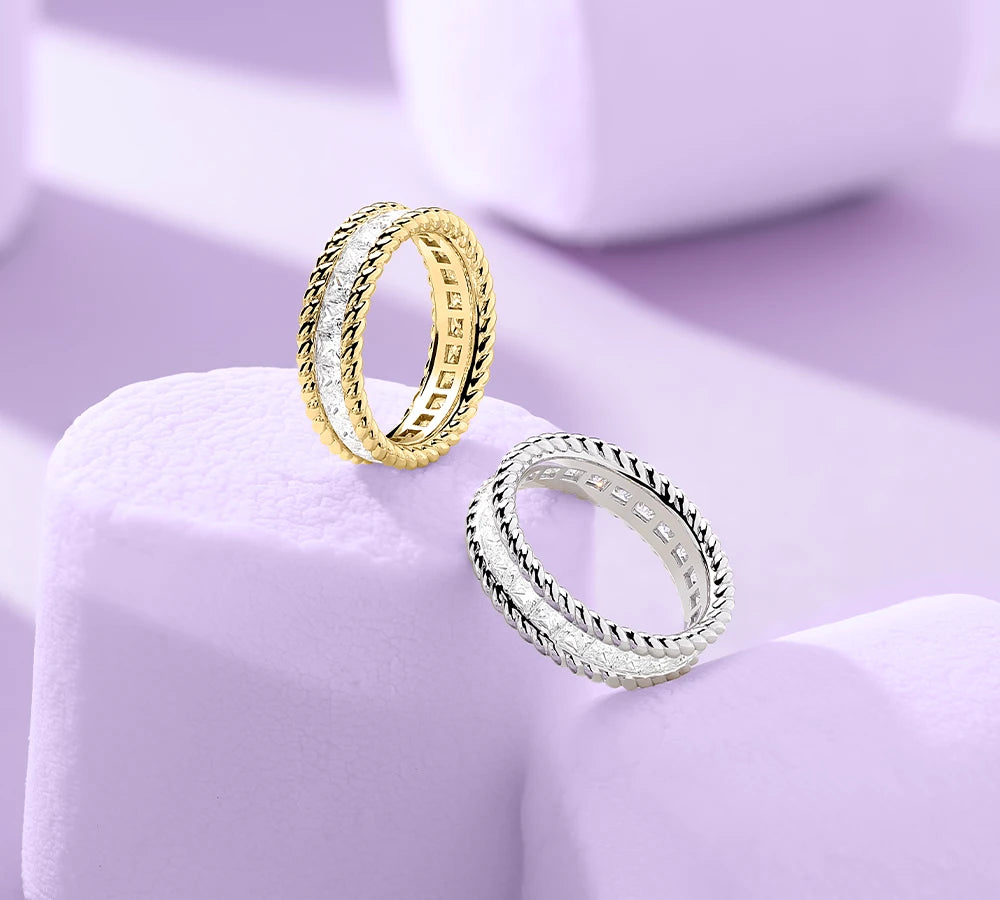 Two APM MONACO torsade rings in yellow gold and silver on light purple marshmallows