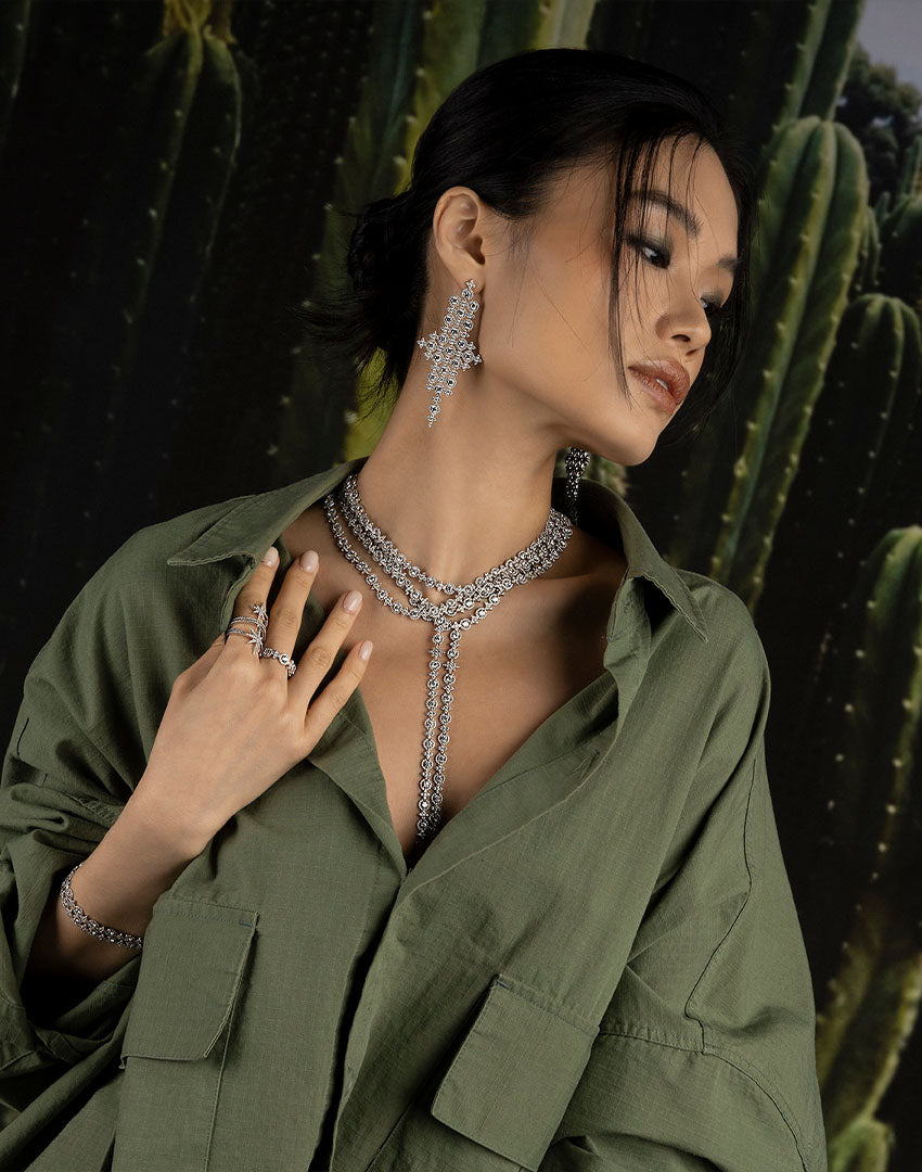 Woman wearing a green outfit with apm monaco jewelry from Meteorites collection against a cactus background