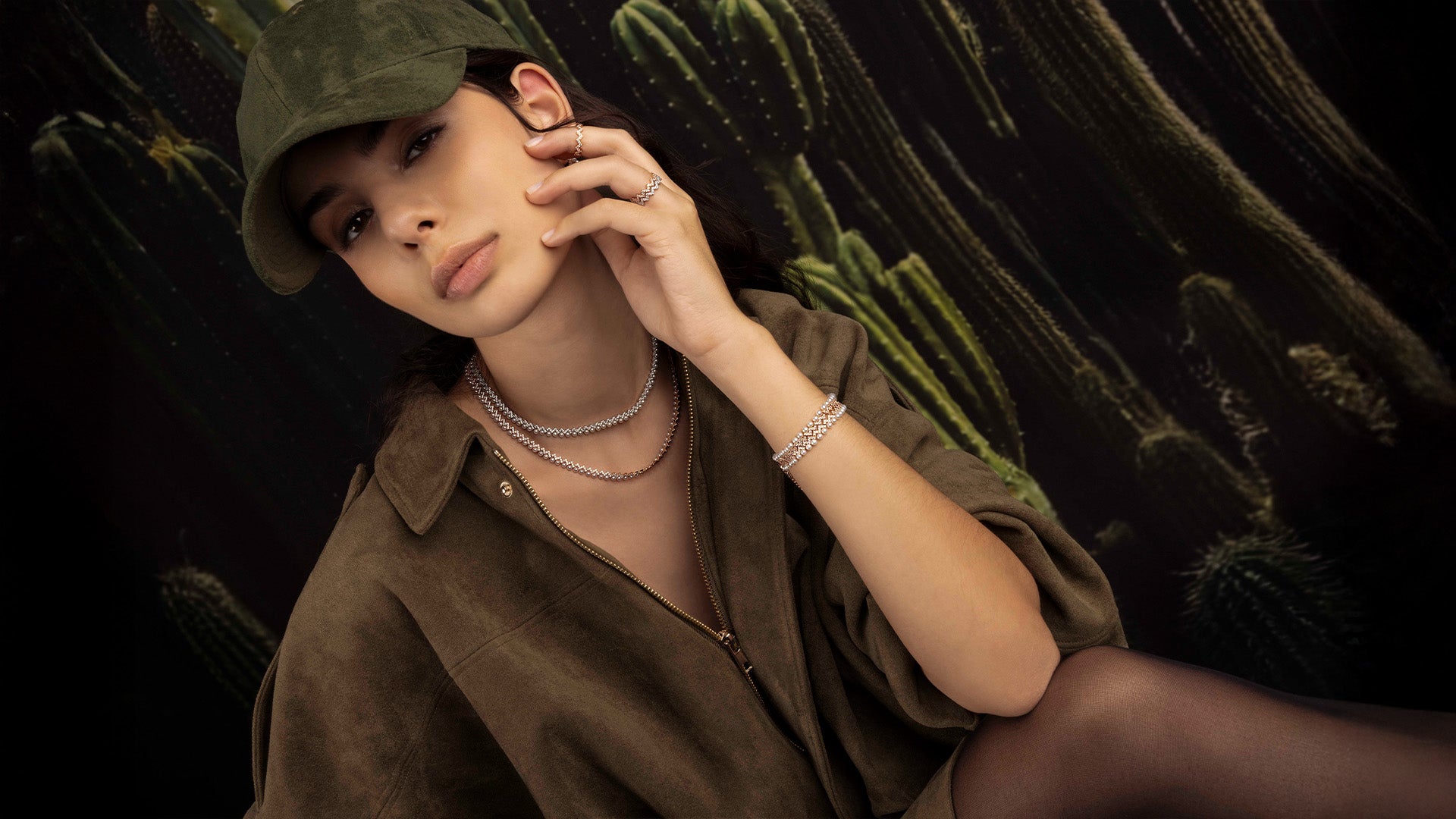 Woman wearing apm monaco up and down pearl jewelry against a dark background with cacti.
