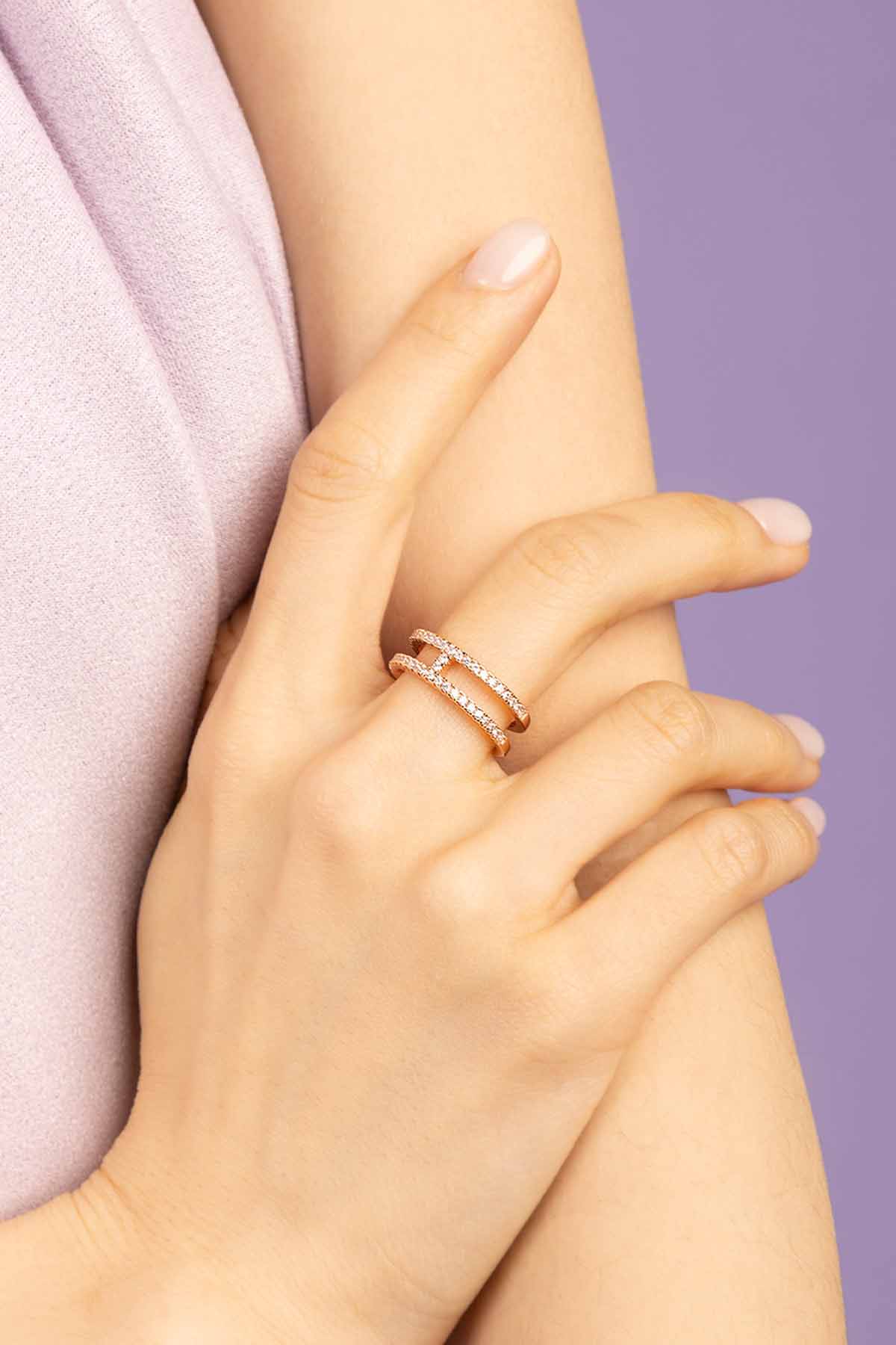 Close-up of a hand wearing APM MONACO double line silver ring on a light purple background