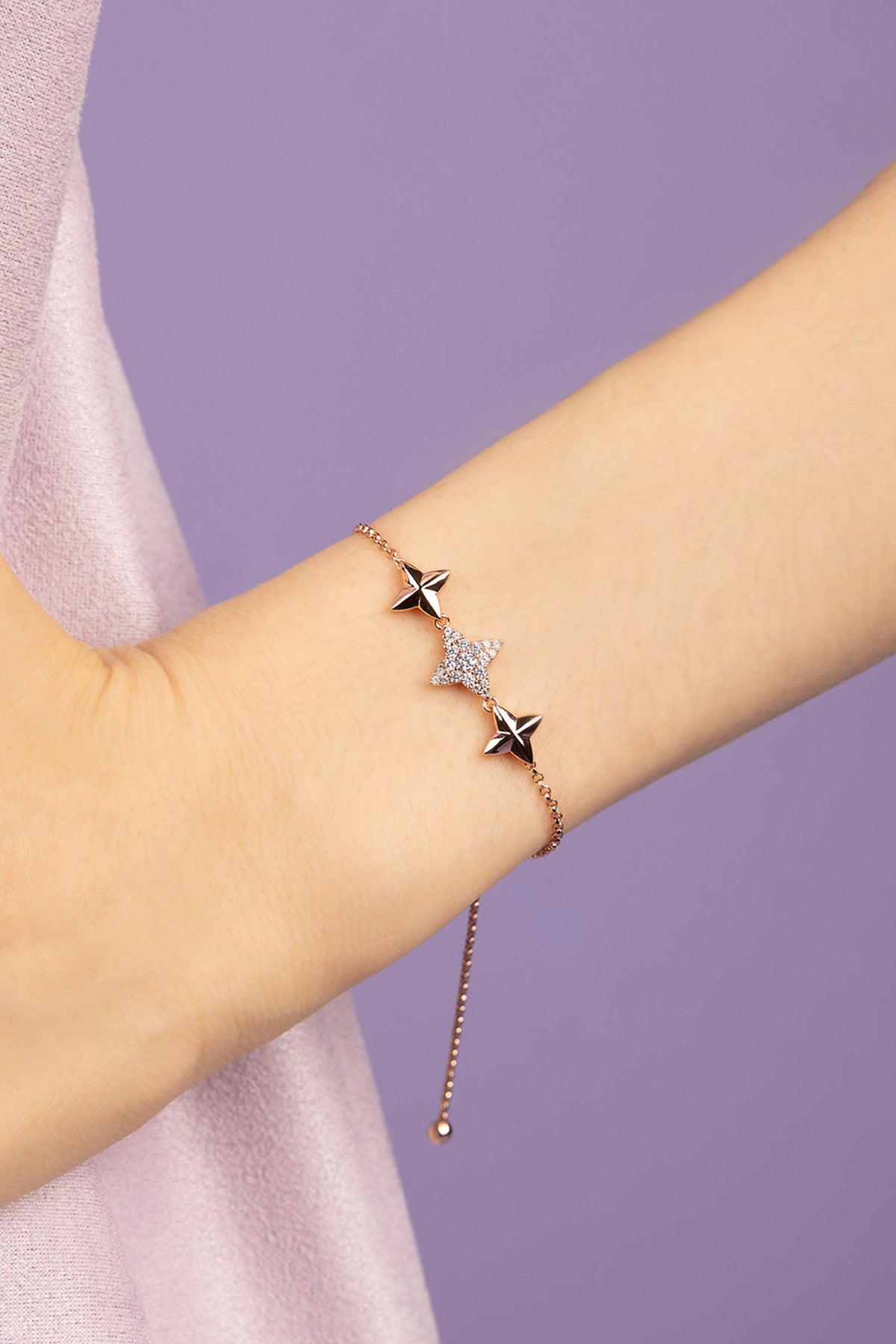 Bracelet with star and zirconia design on a wrist against a purple background