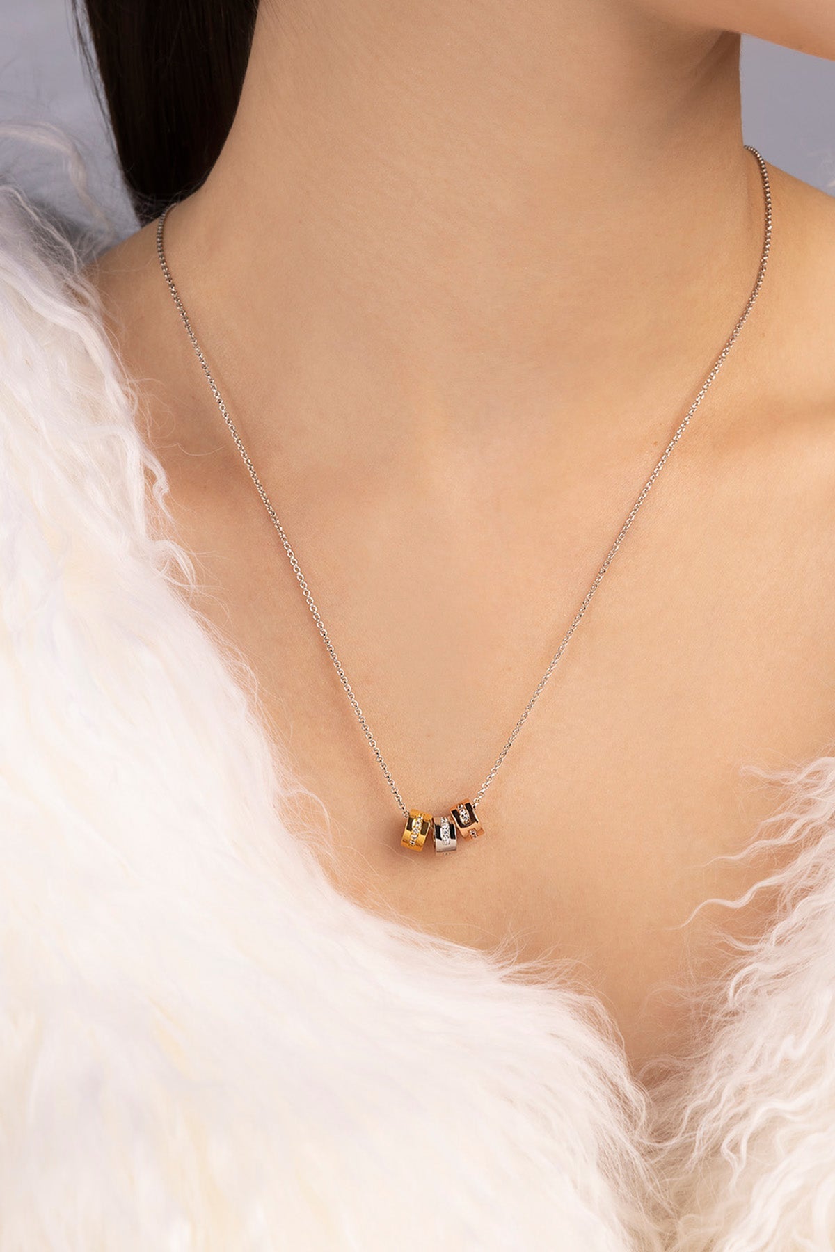 Necklace with small beads worn by a person against a neutral background