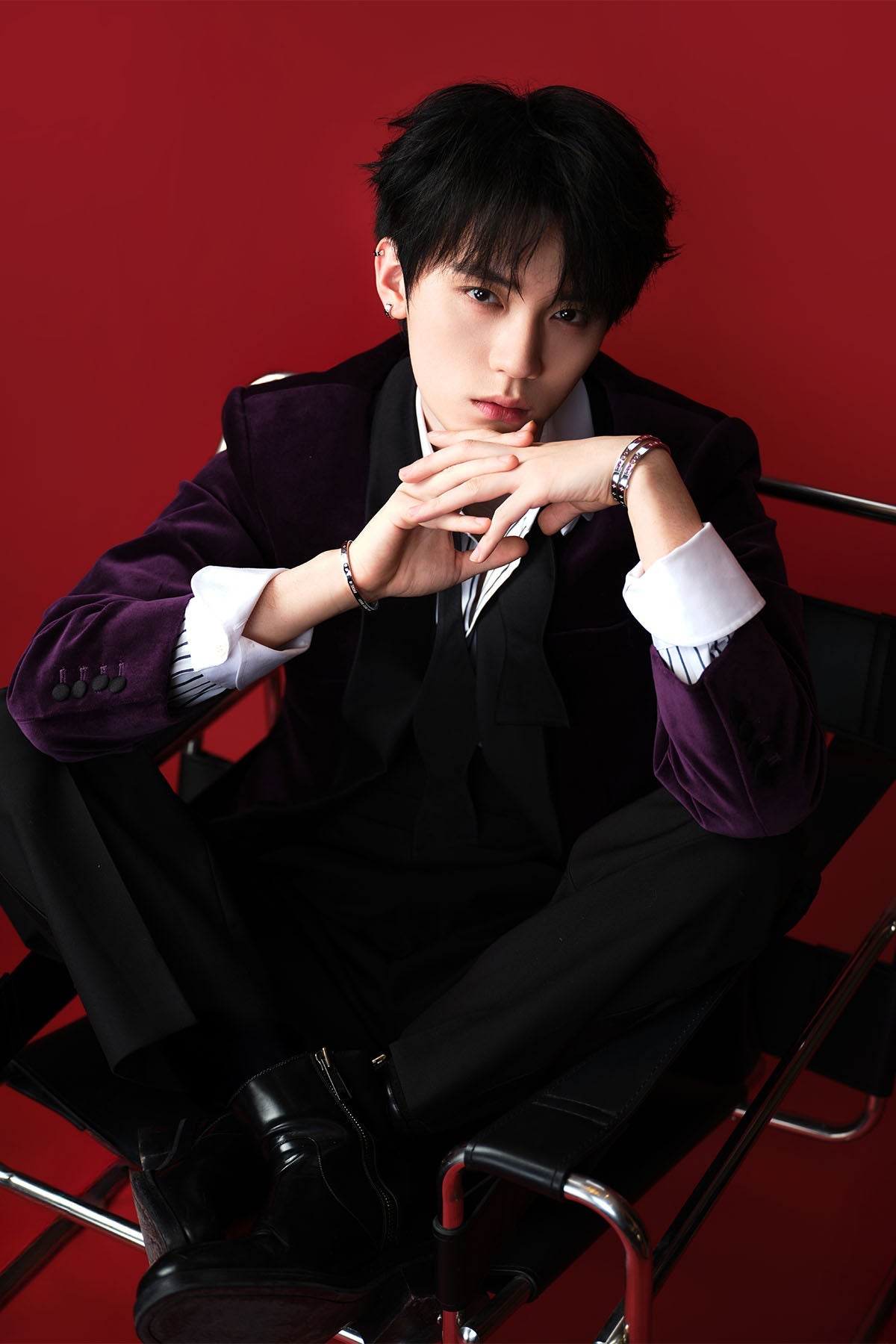 Model wearing a dark suit with a red background