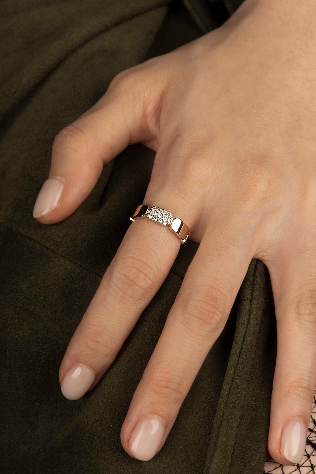 Close-up of a hand wearing a diamond ring on a dark fabric background