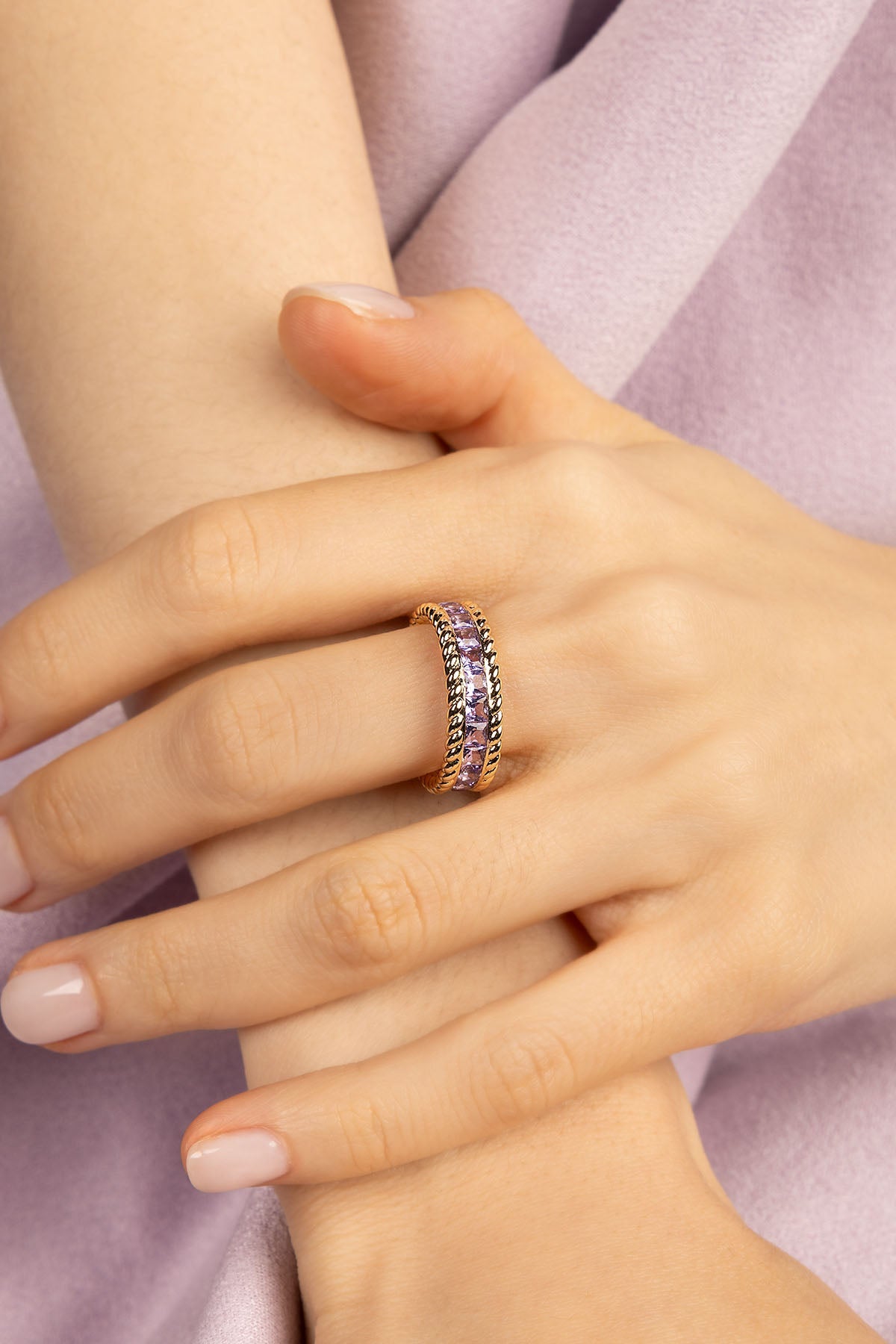 Model wearing yellow gold ring with purple zirconia stones