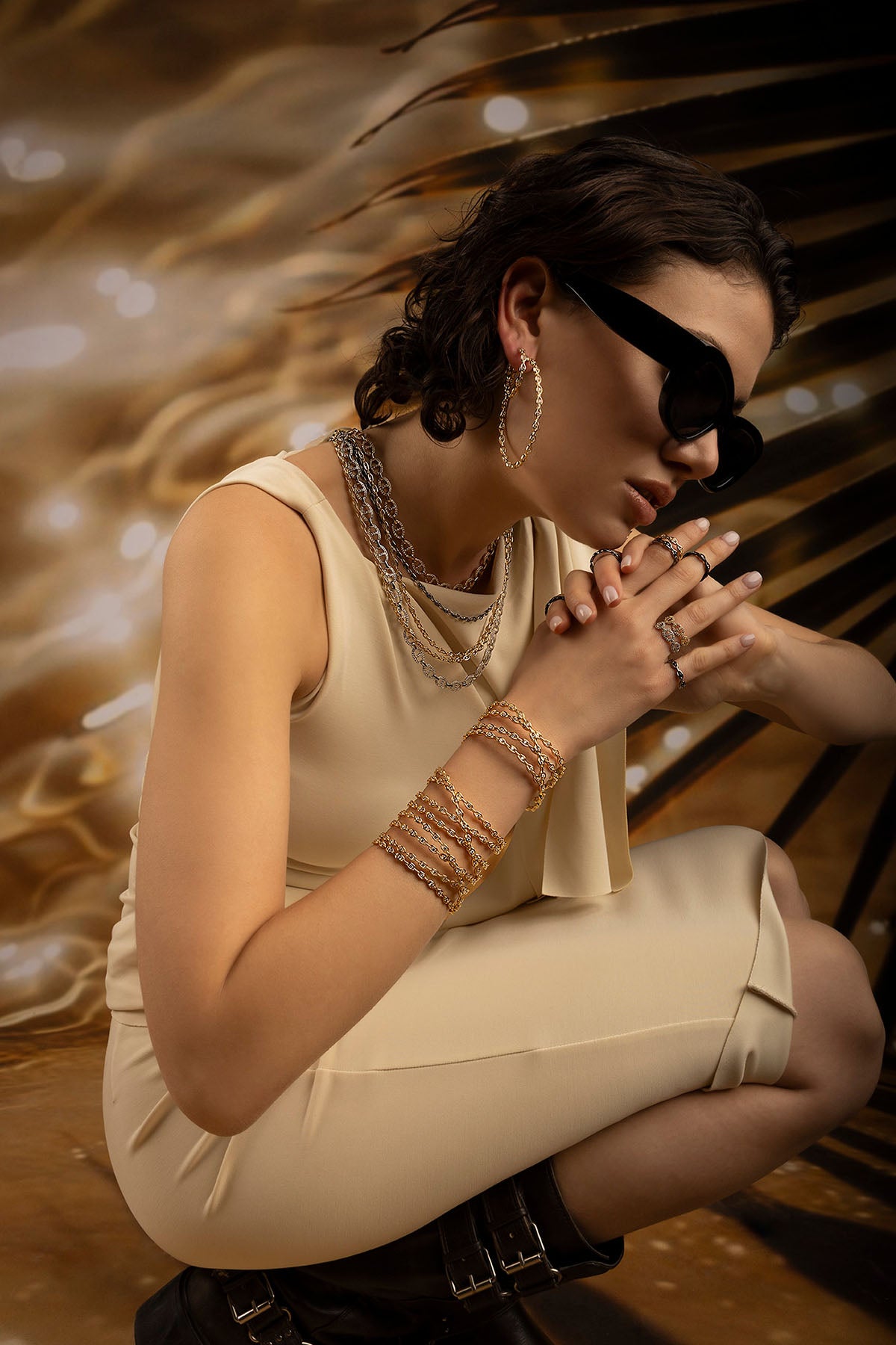 Woman in a beige dress with jewelry against a blurred background