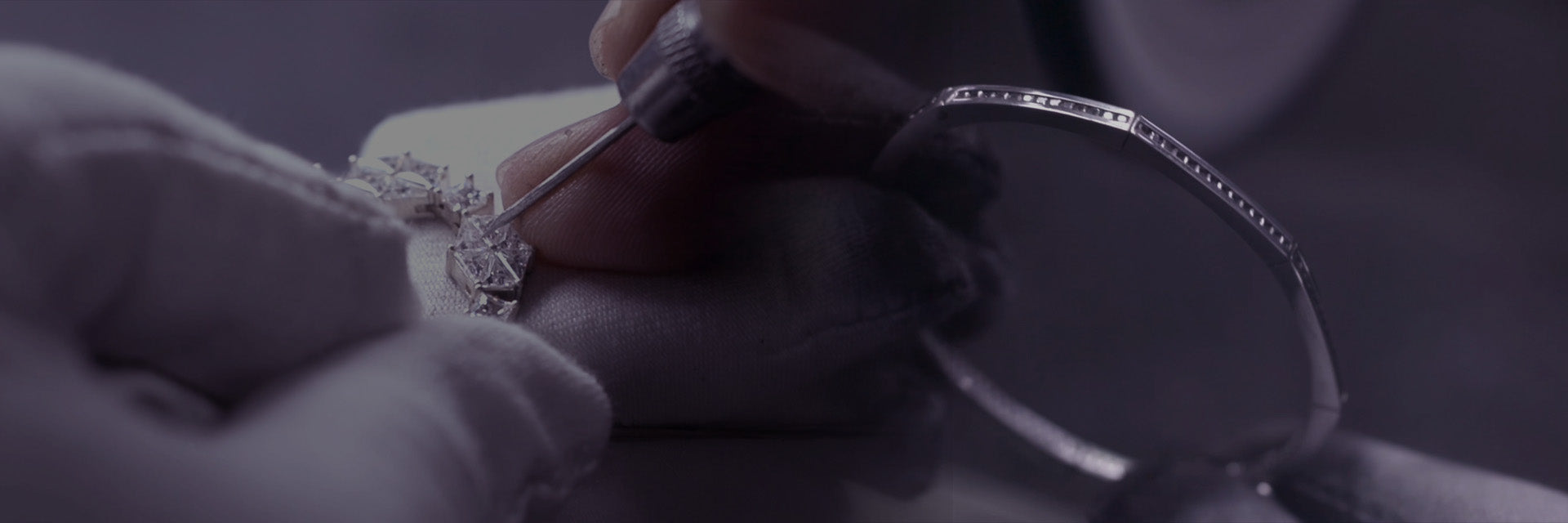 Close-up of hands working on a piece of jewelry with intricate designs.