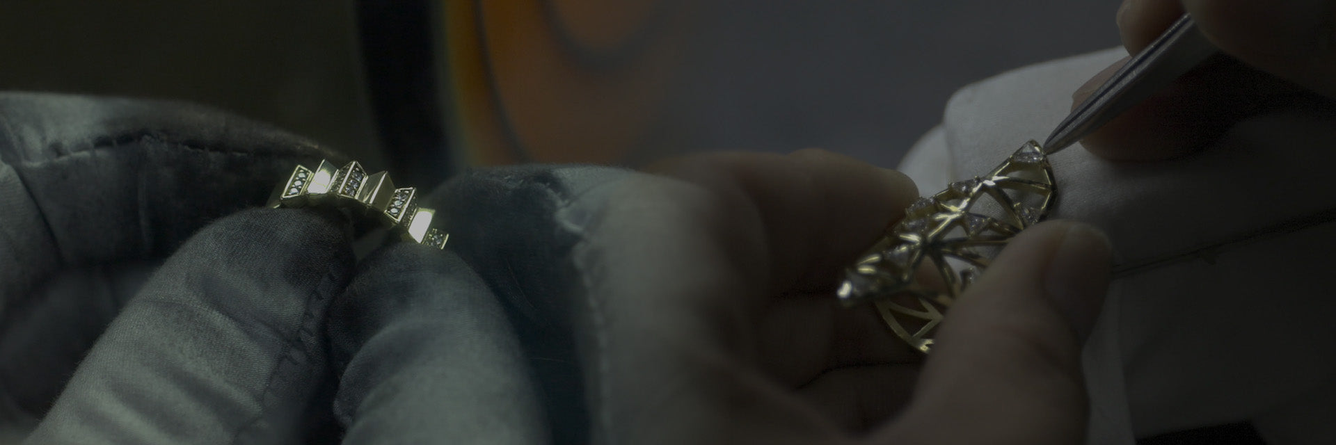 Close-up of hands working on a piece of jewelry with intricate designs.