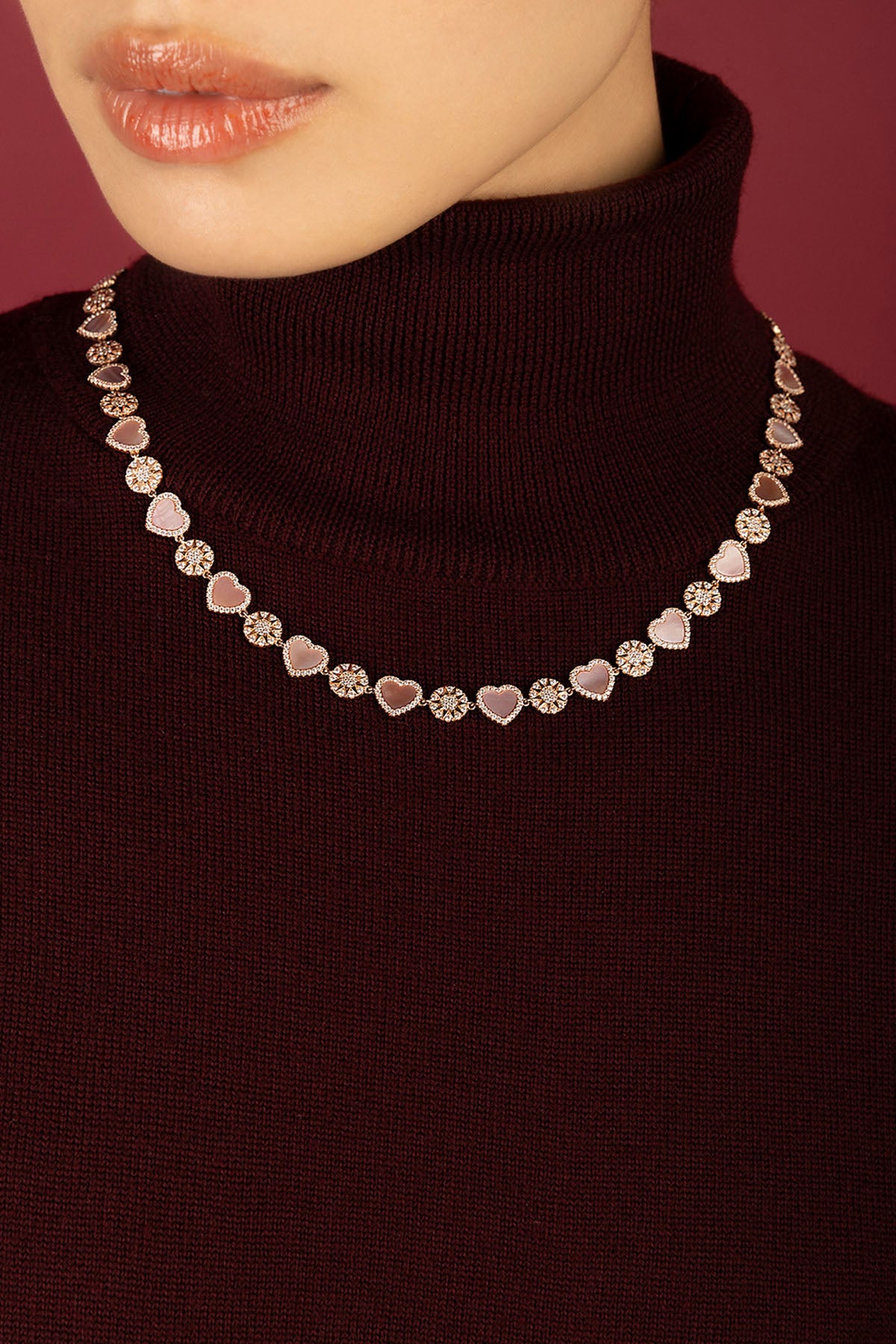Woman wearing APM necklace, hearts and blooms in soft rosy hues.
