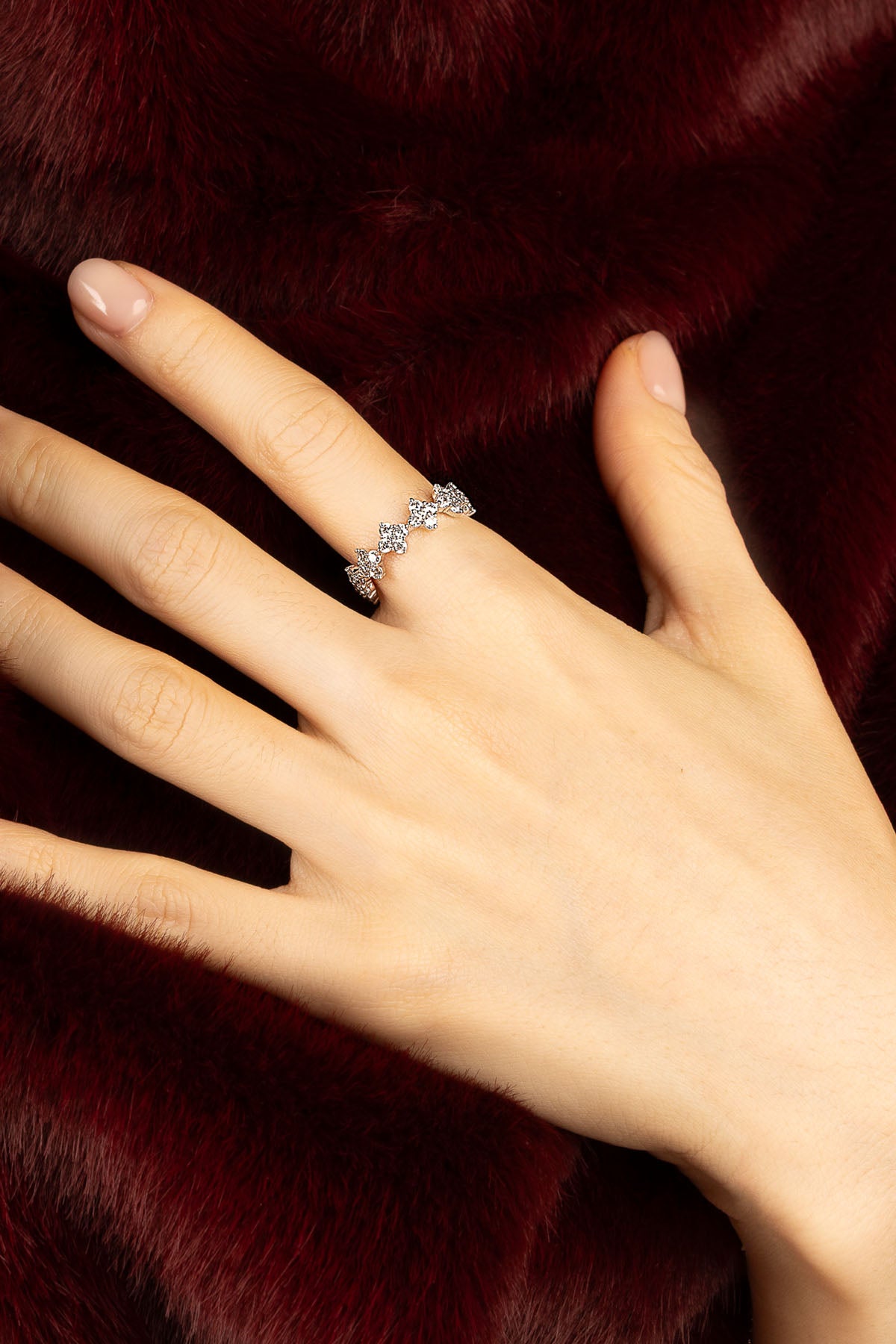 Woman wearing APM ring, a delicate sparkle against velvety crimson.