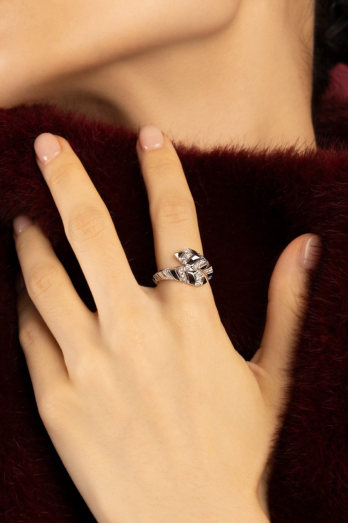 Woman wearing APM ring, a sculpted whisper of graphic elegance against burgundy softness.