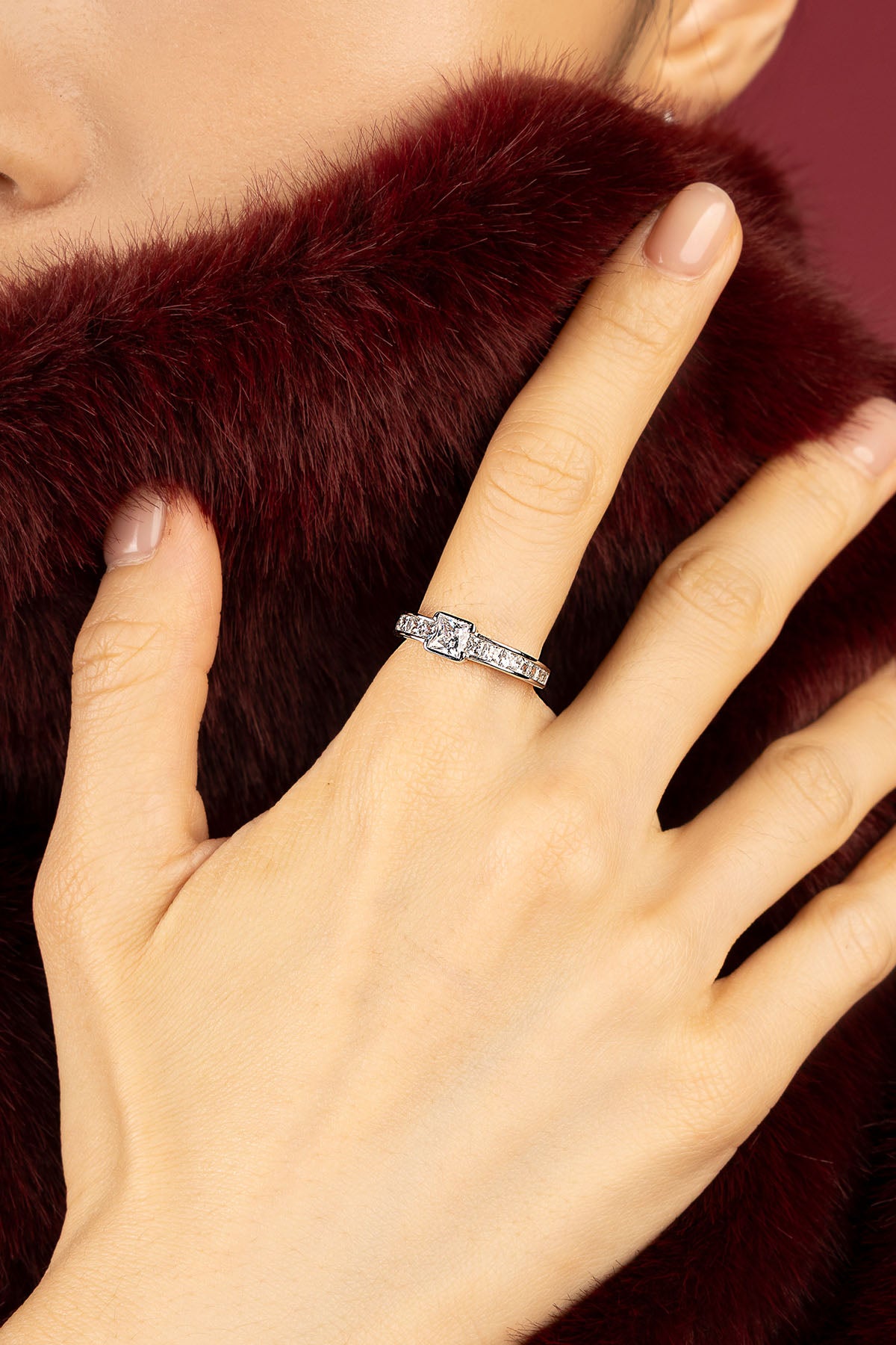 Woman wearing APM Monaco ring, a quiet sparkle against rich burgundy softness.