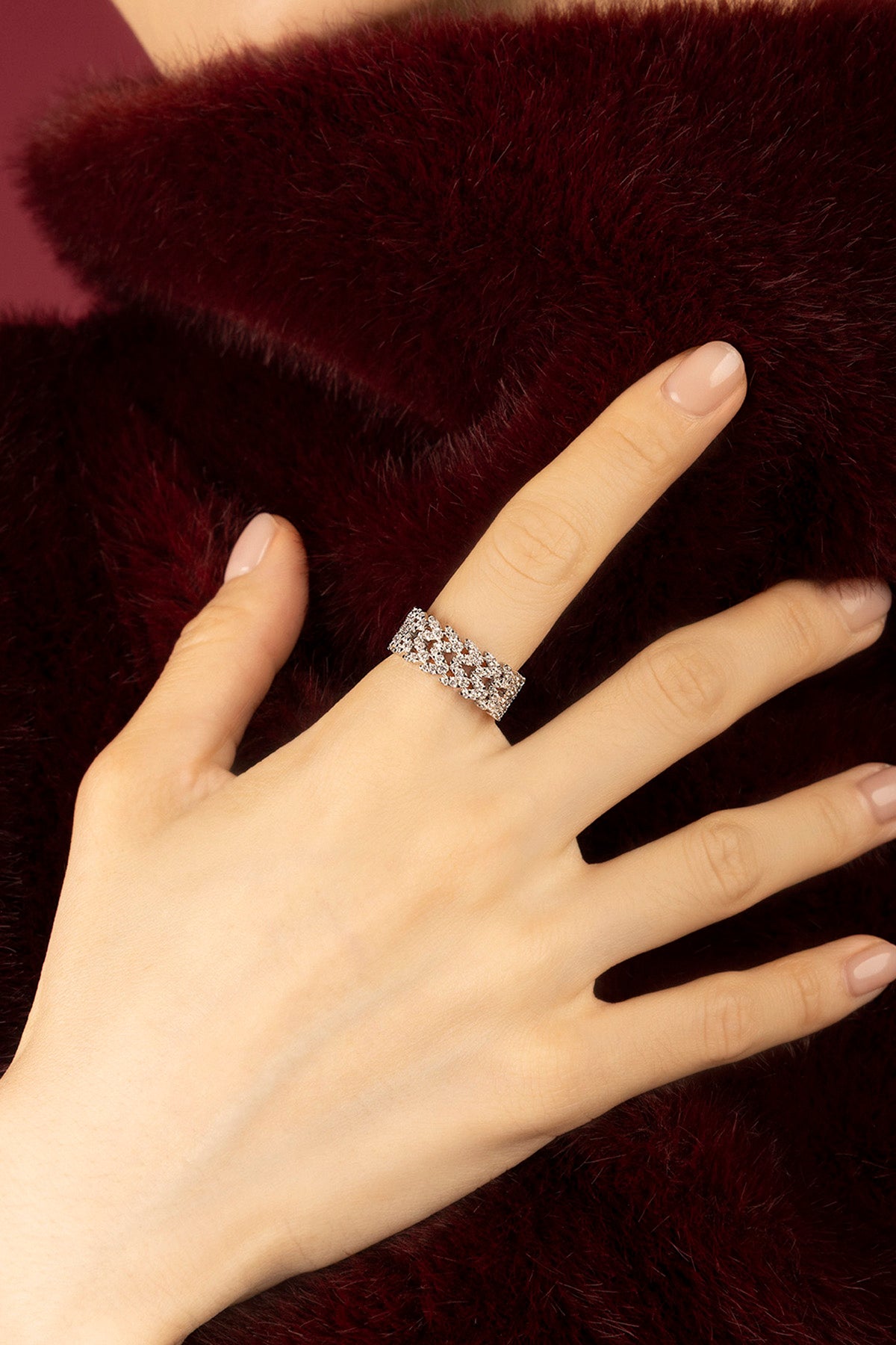 Woman wearing APM ring, a shimmering lace of light against velvet warmth.