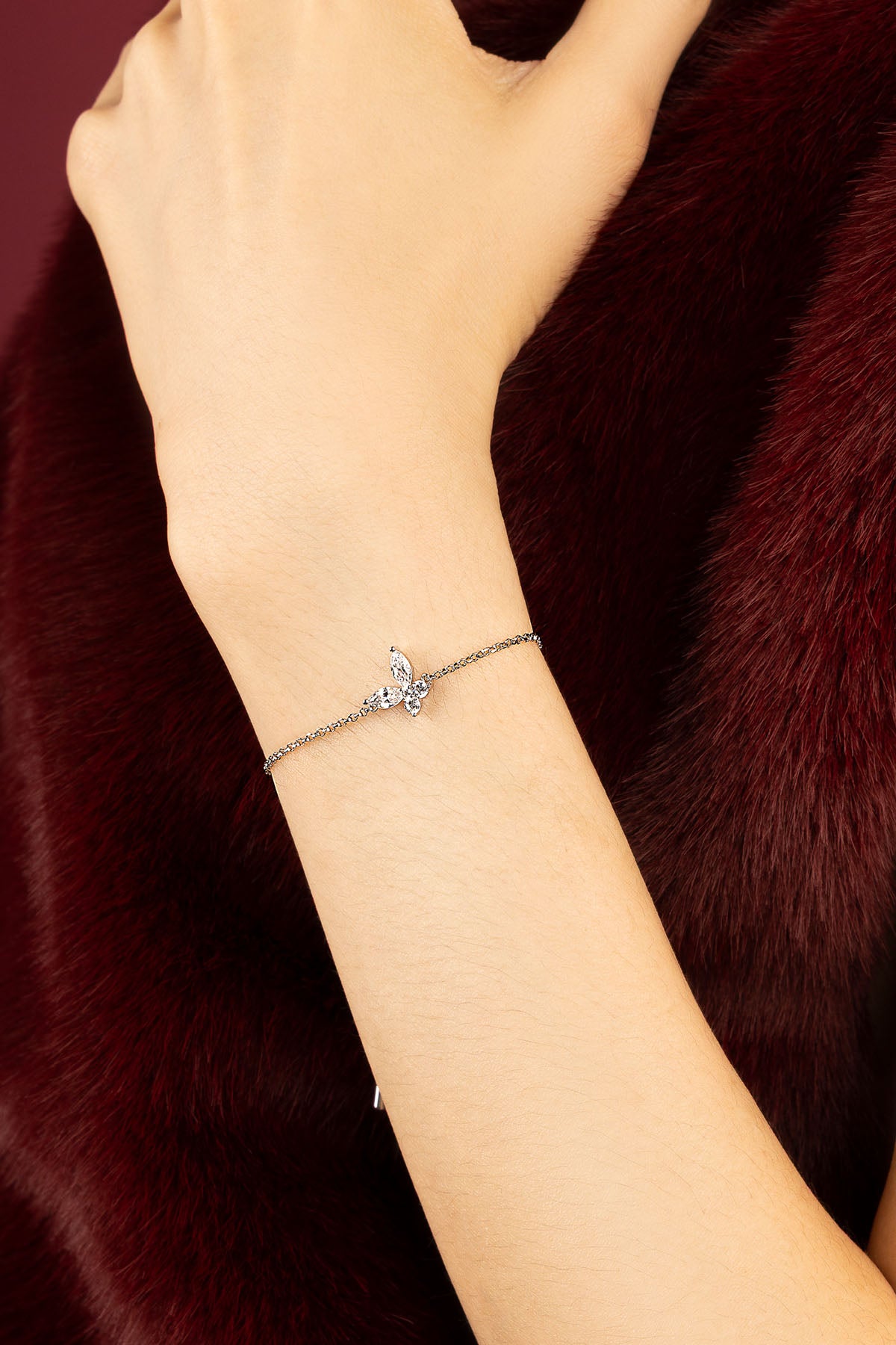 Woman wearing APM butterfly bracelet, delicate sparkle against rich winter tones.