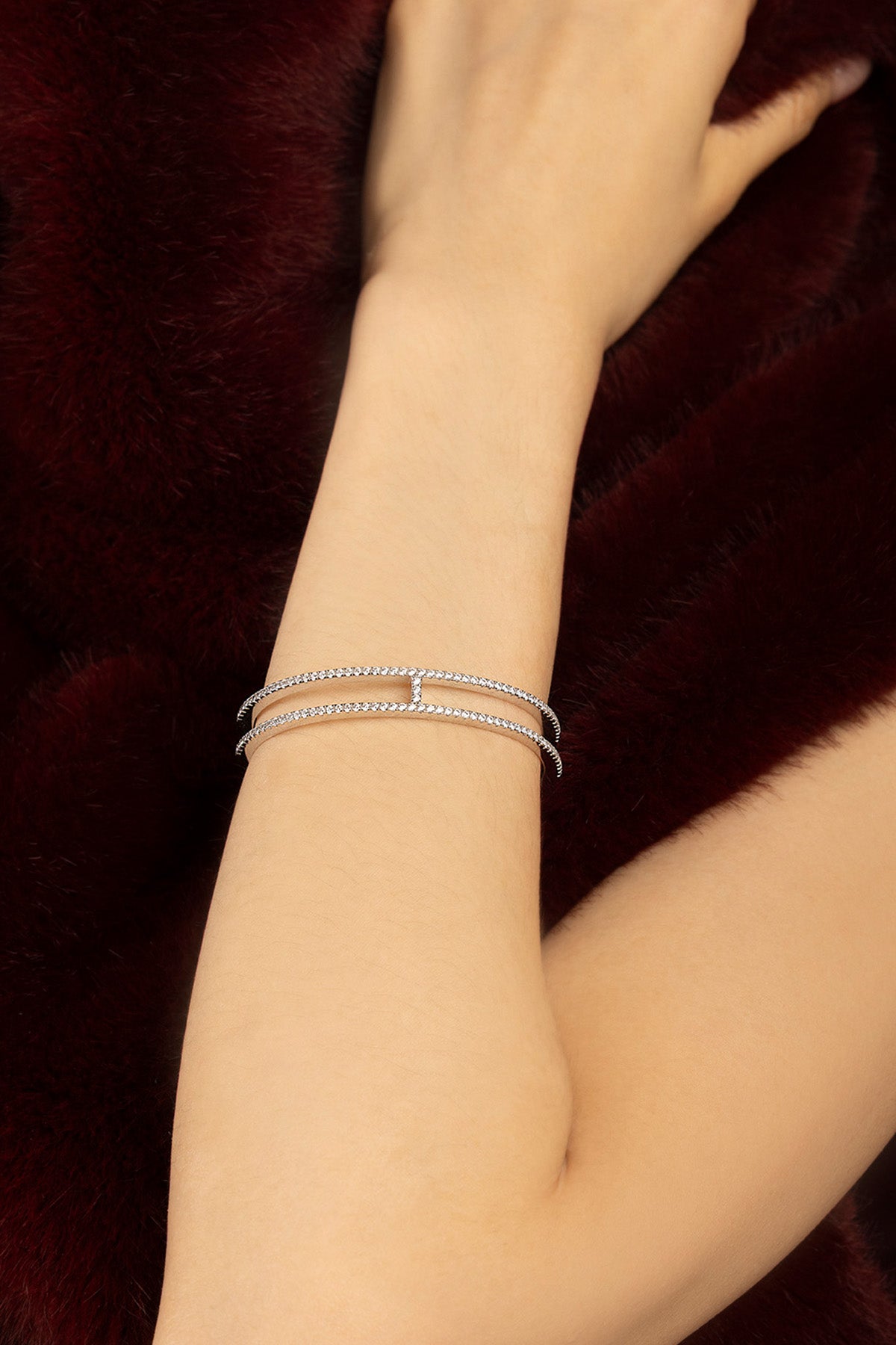 Woman wearing APM Monaco bangle, a double line of quiet sparkle against velvet.
