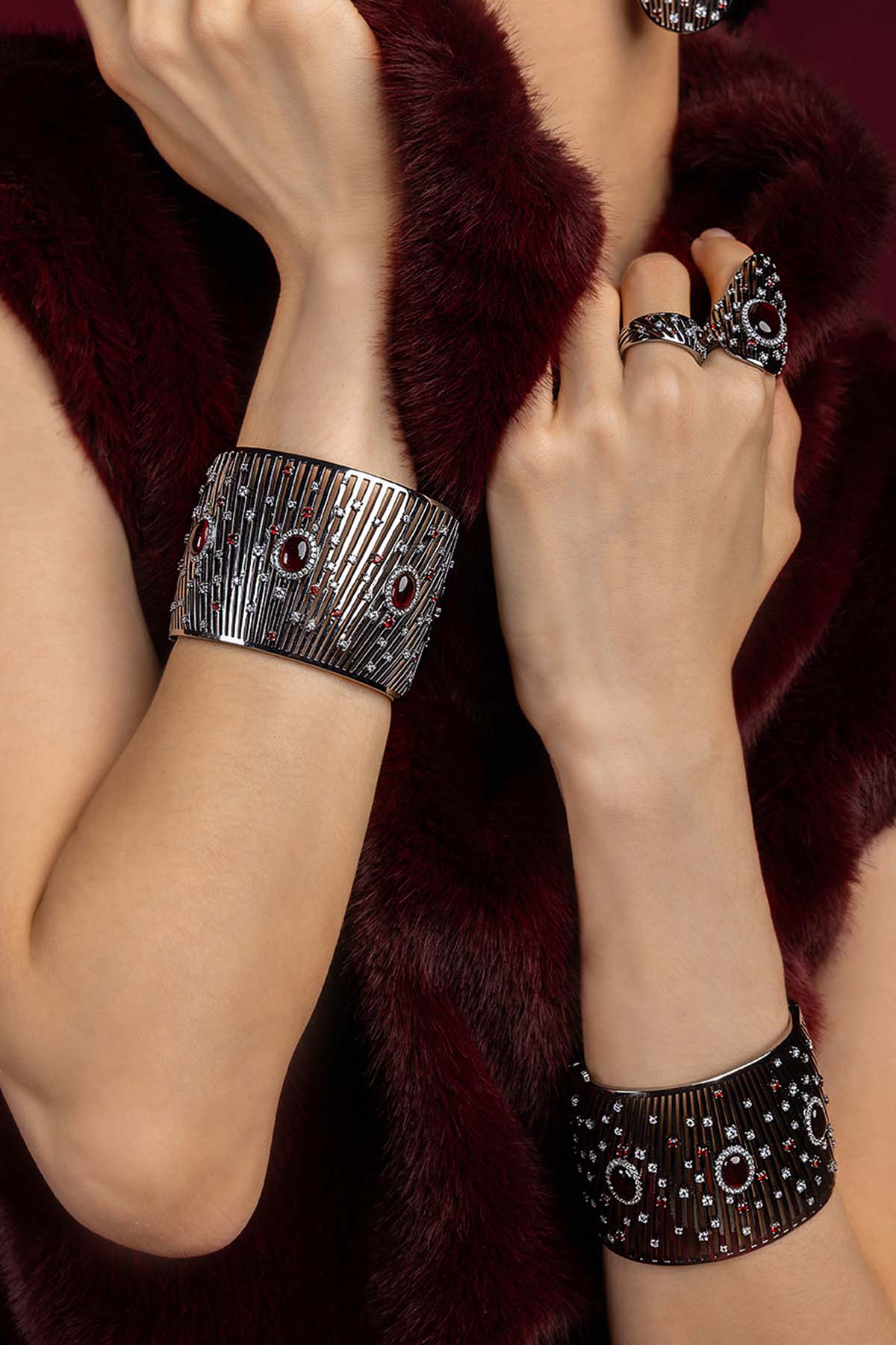 Woman wearing APM cuff and rings, bold rhodium finish meets crimson allure.