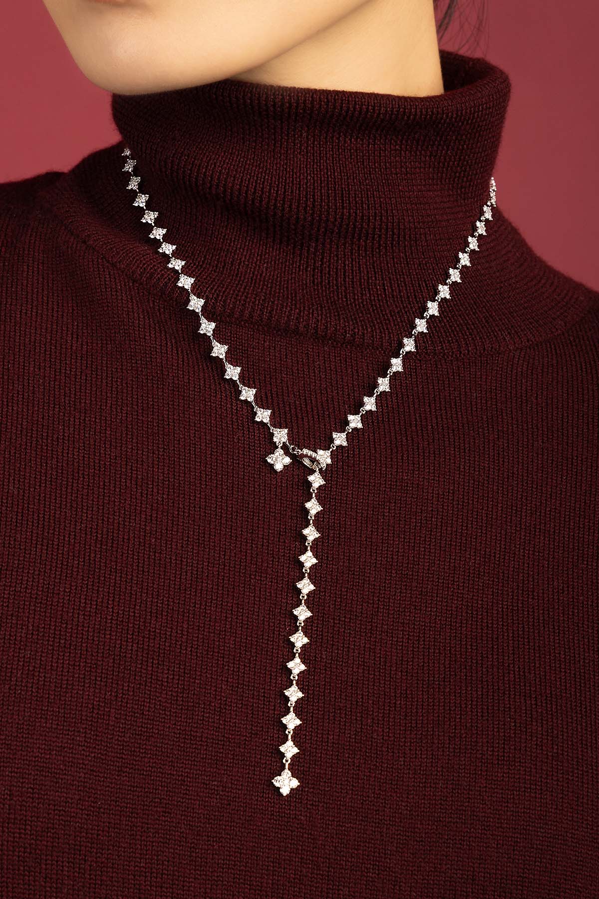 Woman wearing APM Monaco lariat necklace, a shimmering cascade of quiet elegance.