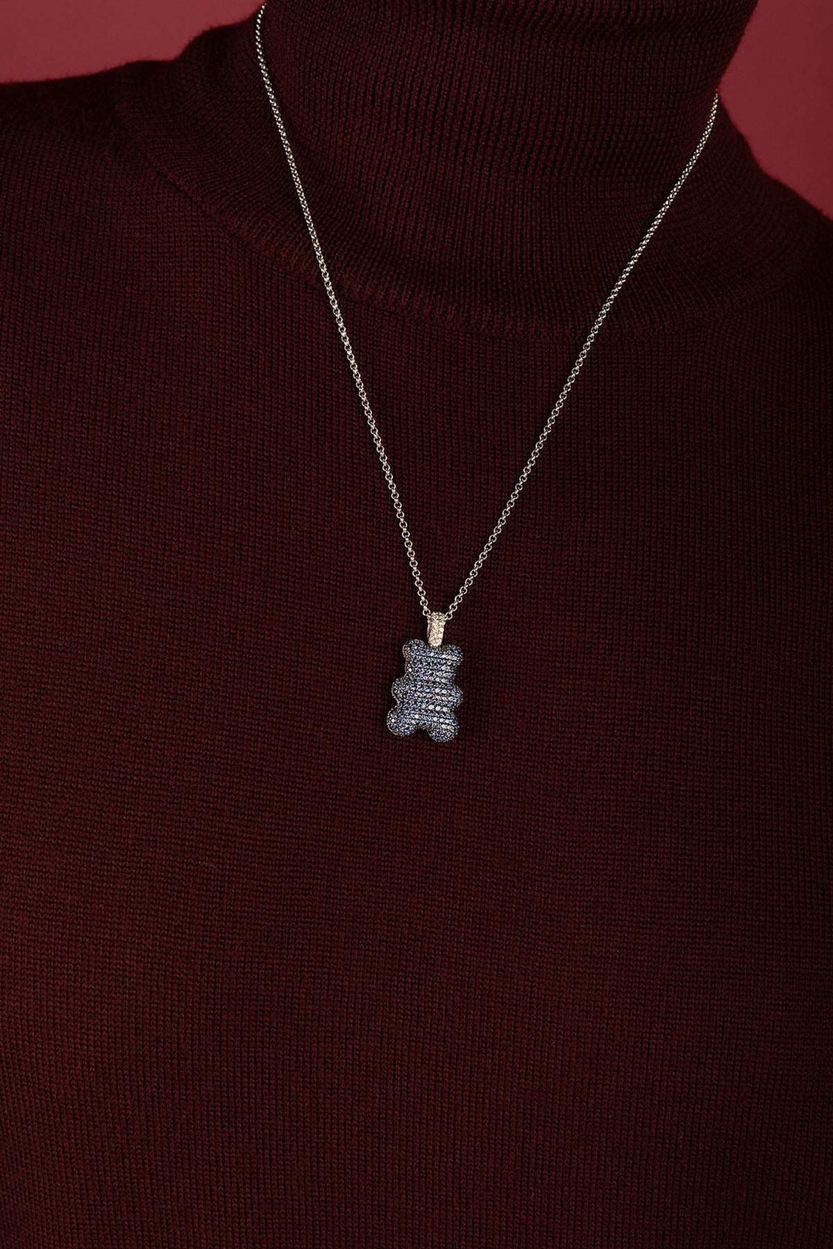 Woman wearing APM bear pendant necklace, a playful charm on burgundy knitwear.