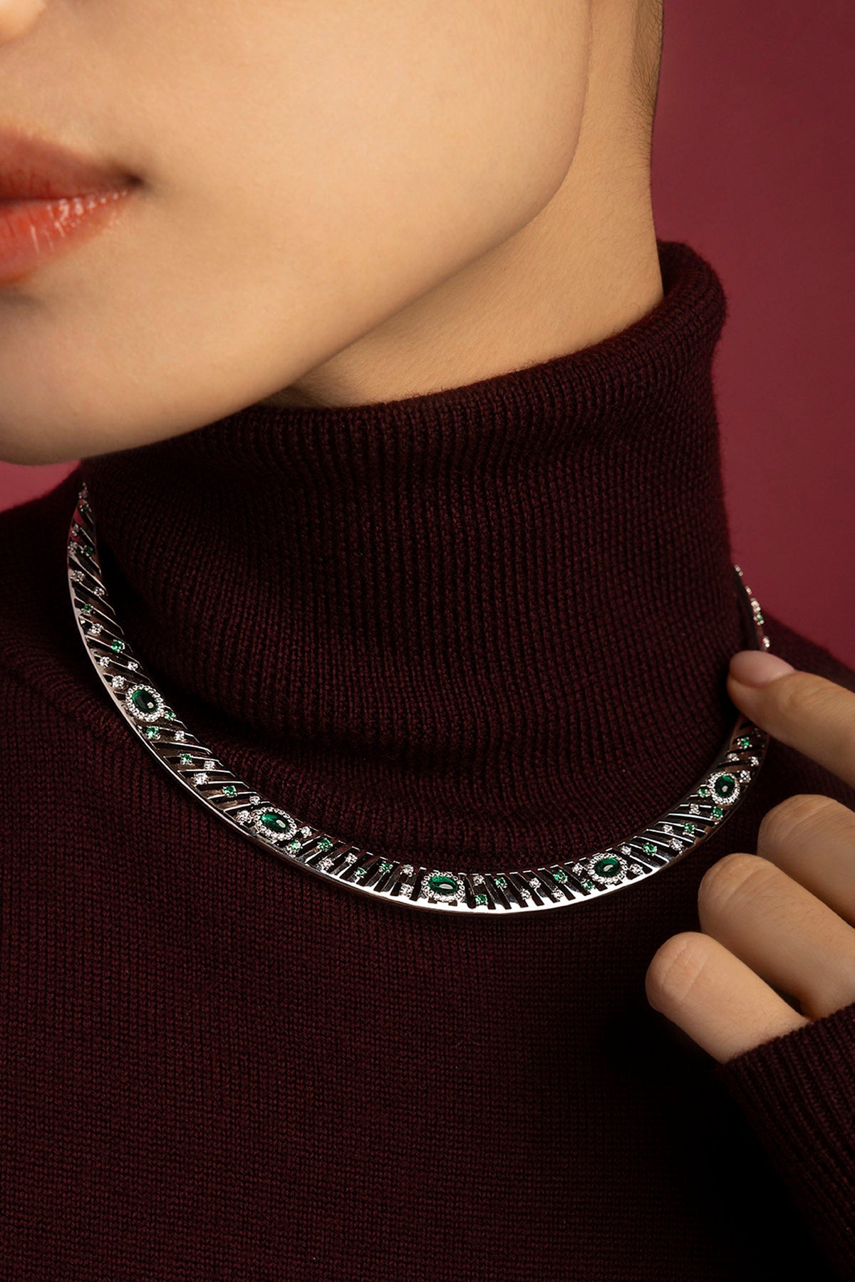 Woman wearing APM Monaco collar necklace, radiant green accents on rhodium finish elegance.