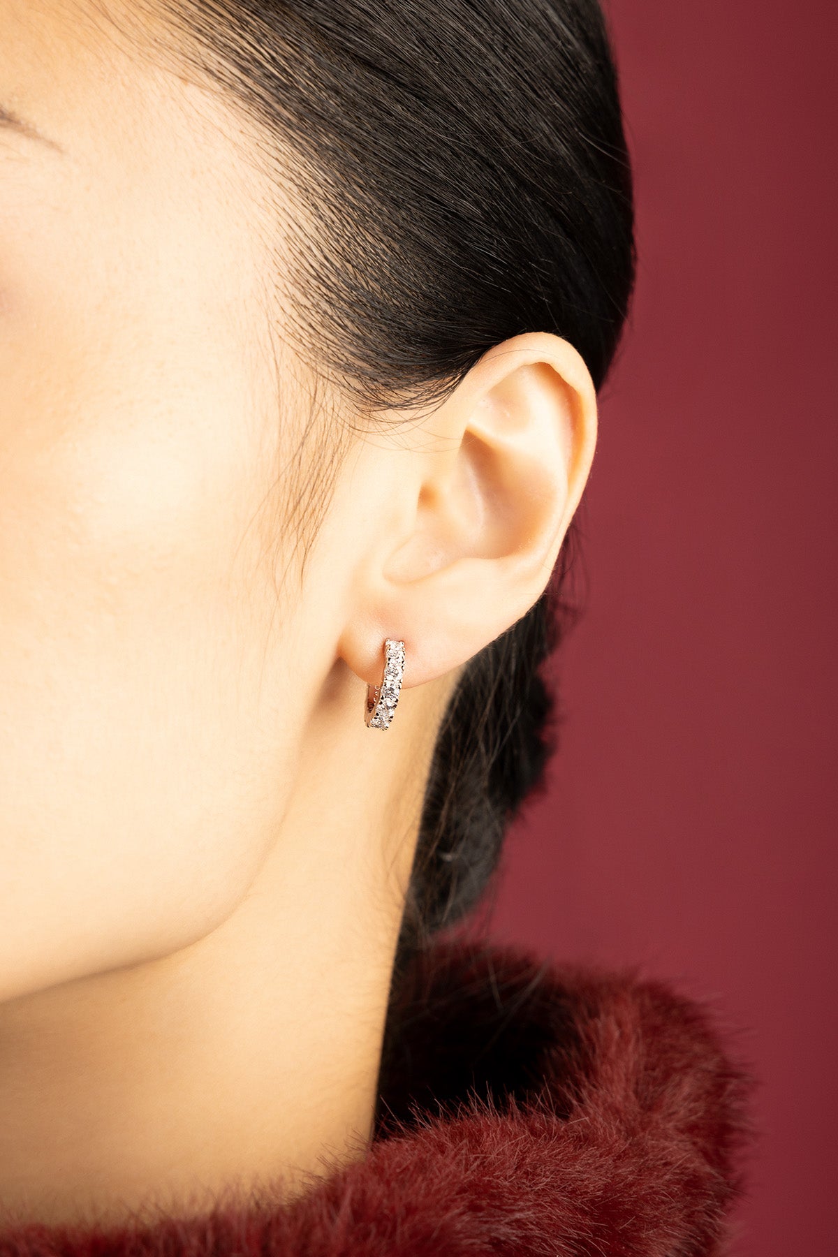 Woman wearing APM Monaco hoop earrings, a sparkling whisper of modern elegance.