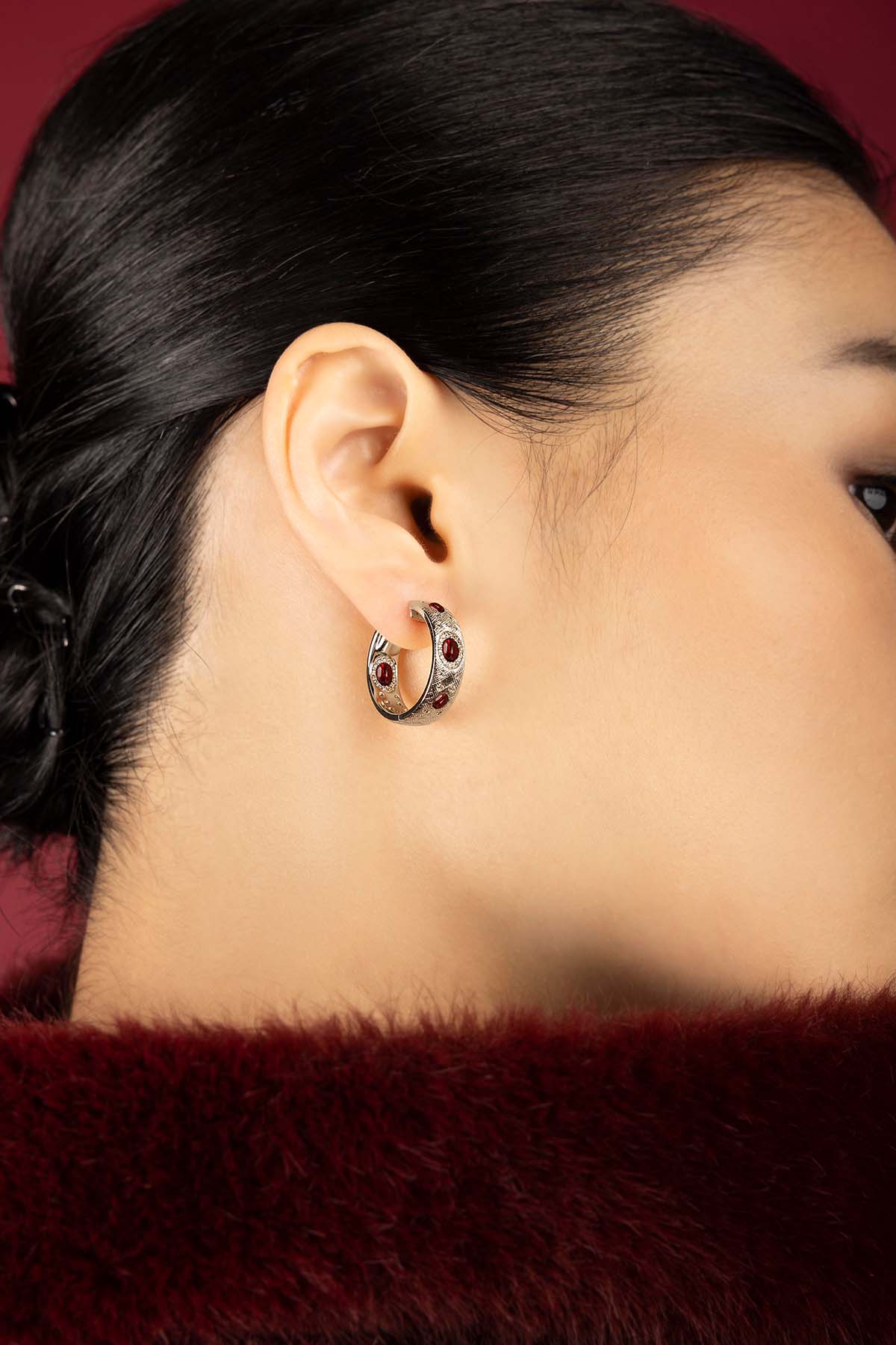 Woman wearing APM Monaco hoop earrings, a bold whisper of crimson elegance.