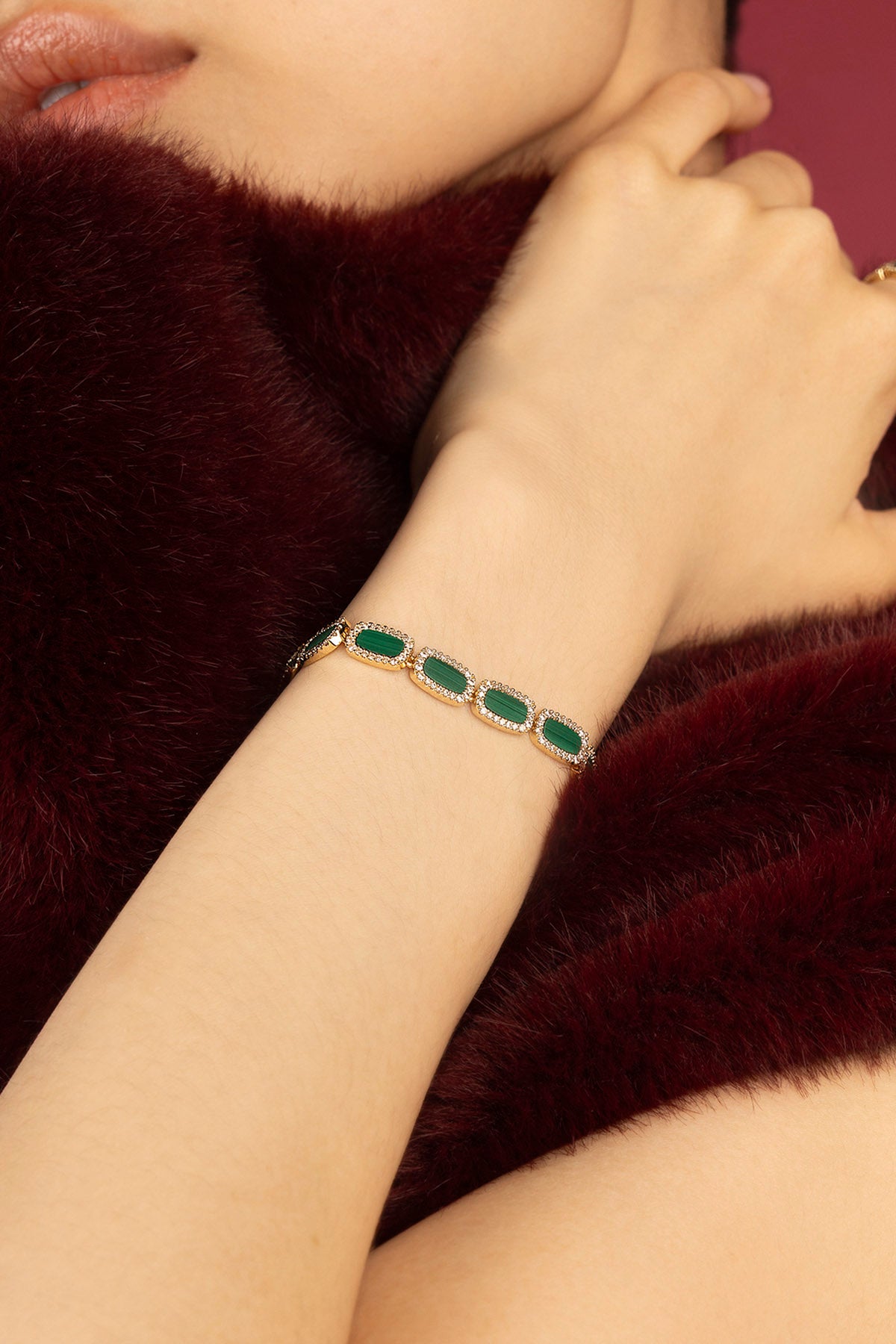 Woman wearing APM bracelet, green hues glowing against wintry elegance.