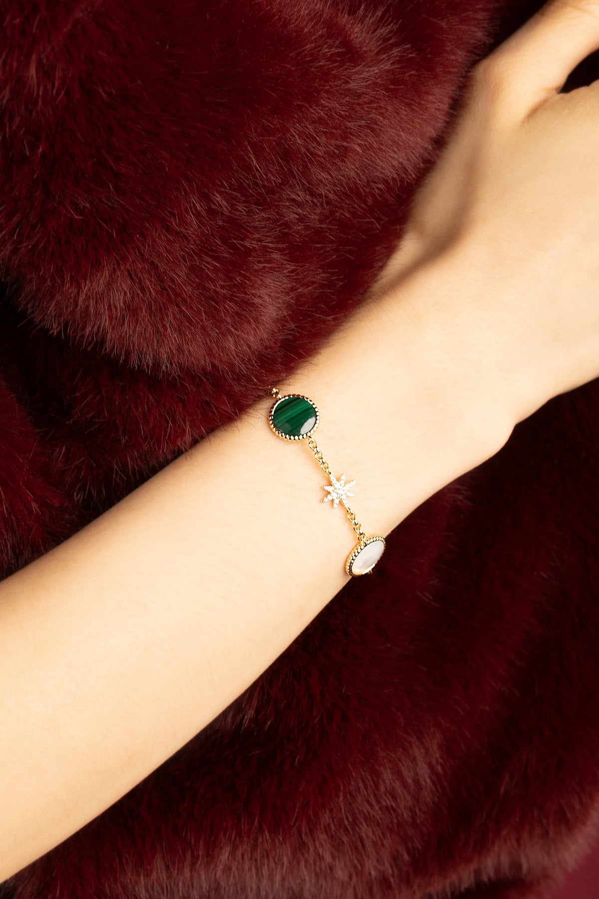 Woman wearing APM Monaco bracelet, a celestial charm against rich winter hues.