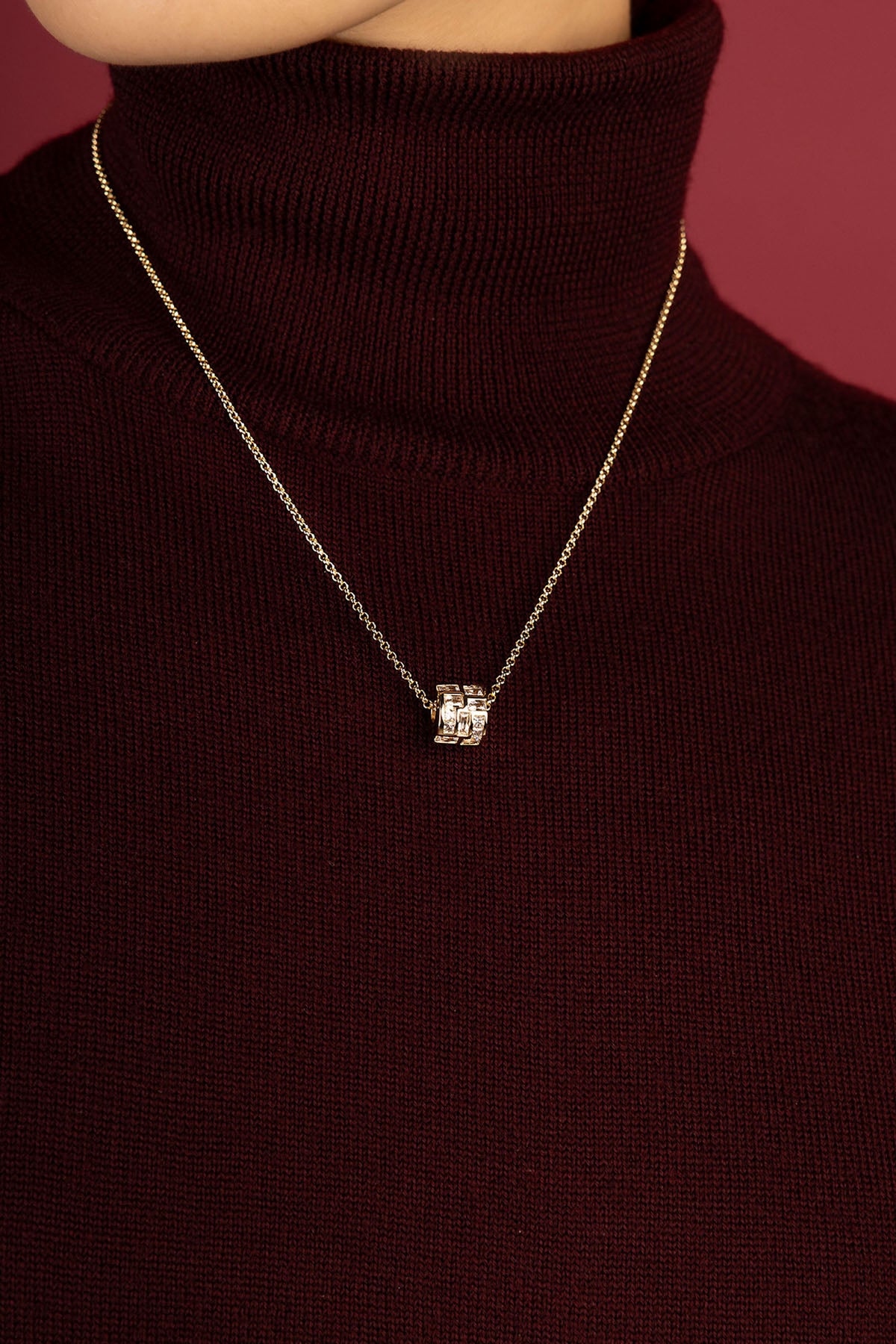 Woman wearing APM Monaco necklace, a quiet spark against burgundy warmth.